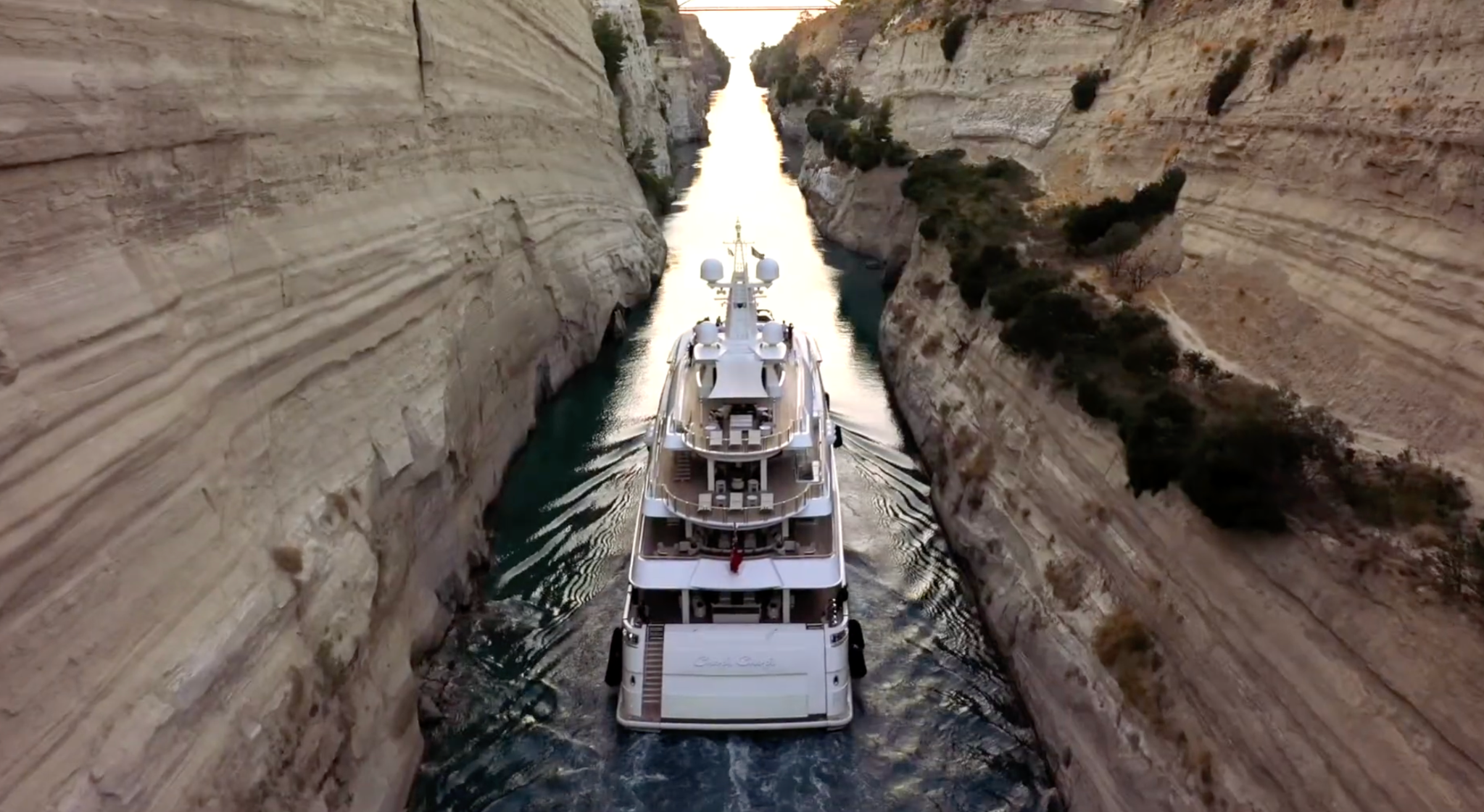 Yacht passing between steep canal cliffs