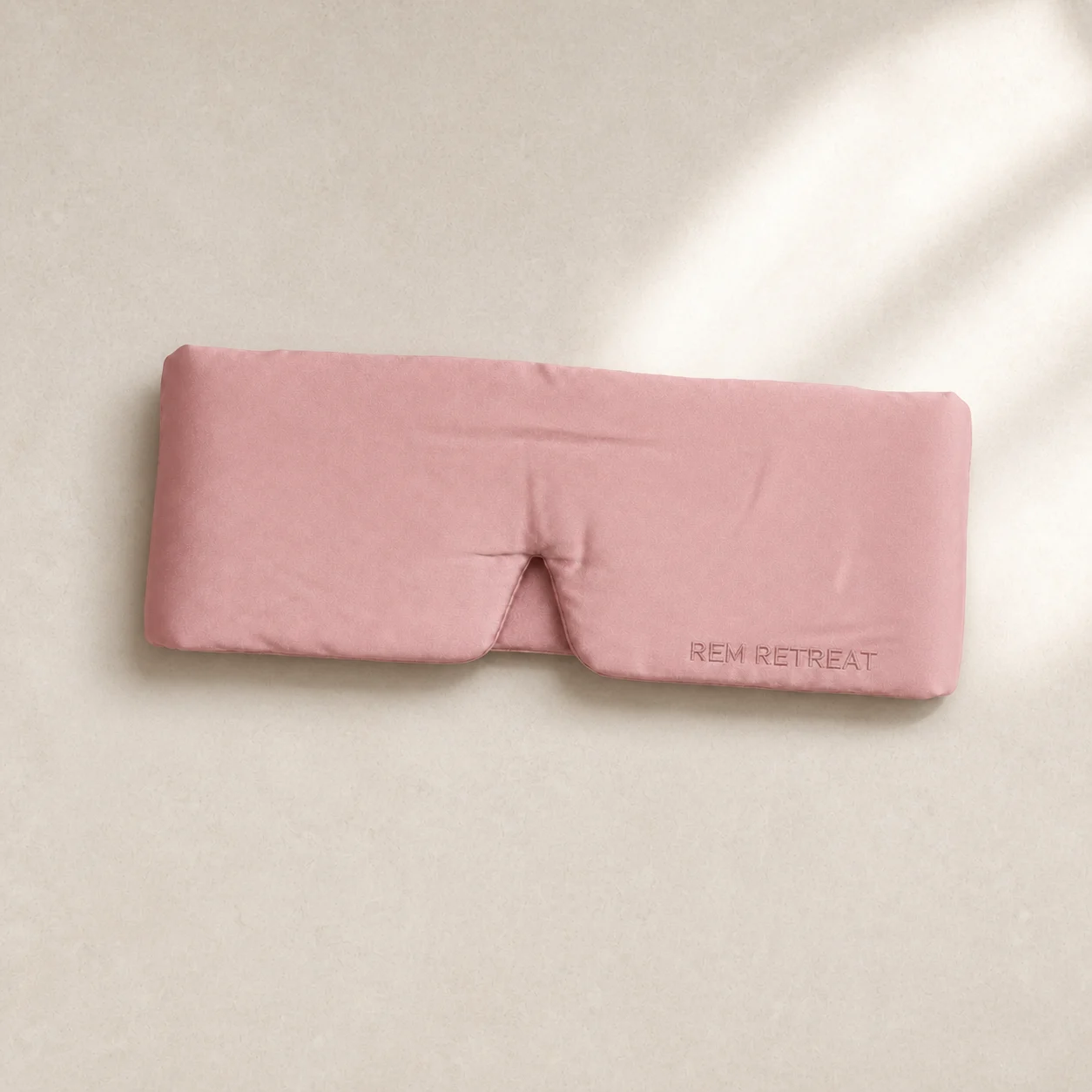 Hush Pink silk sleep mask on pale limestone in soft window light