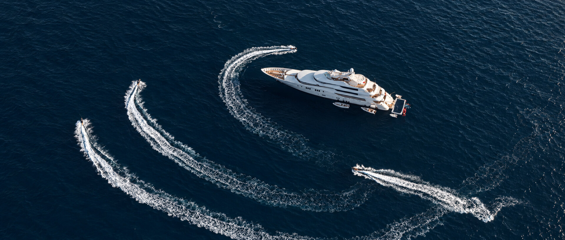 A yacht surrounded by sweeping tender wakes