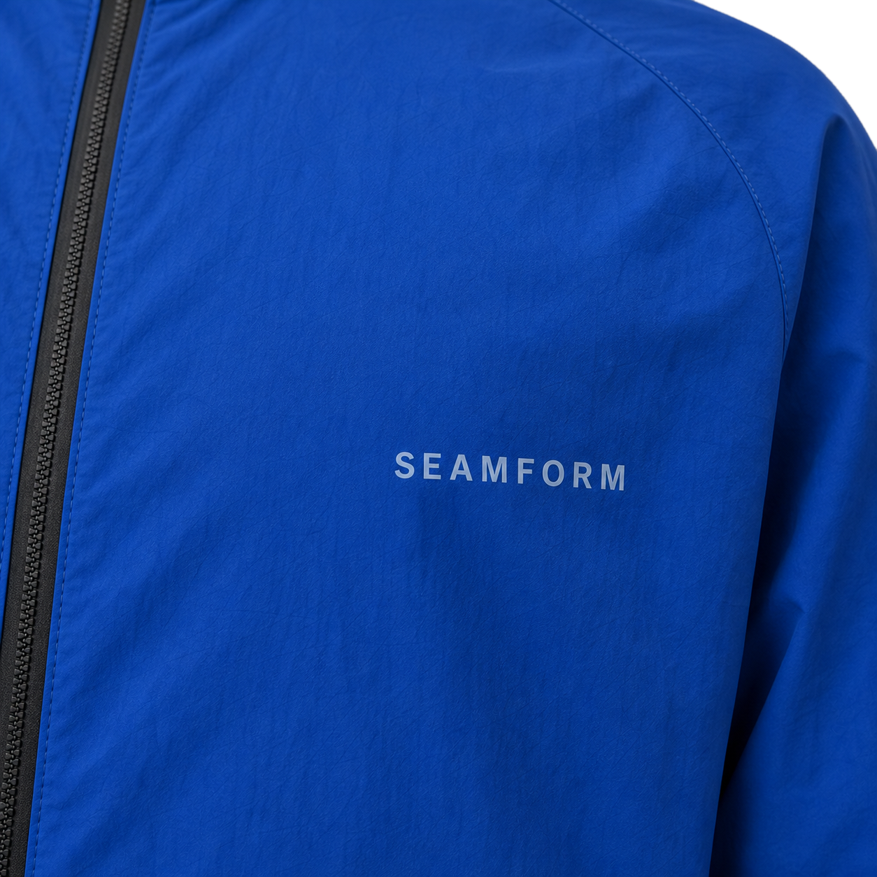 SEAMFORM SF-01 close study — the restrained tonal SEAMFORM chest mark on matte technical nylon.