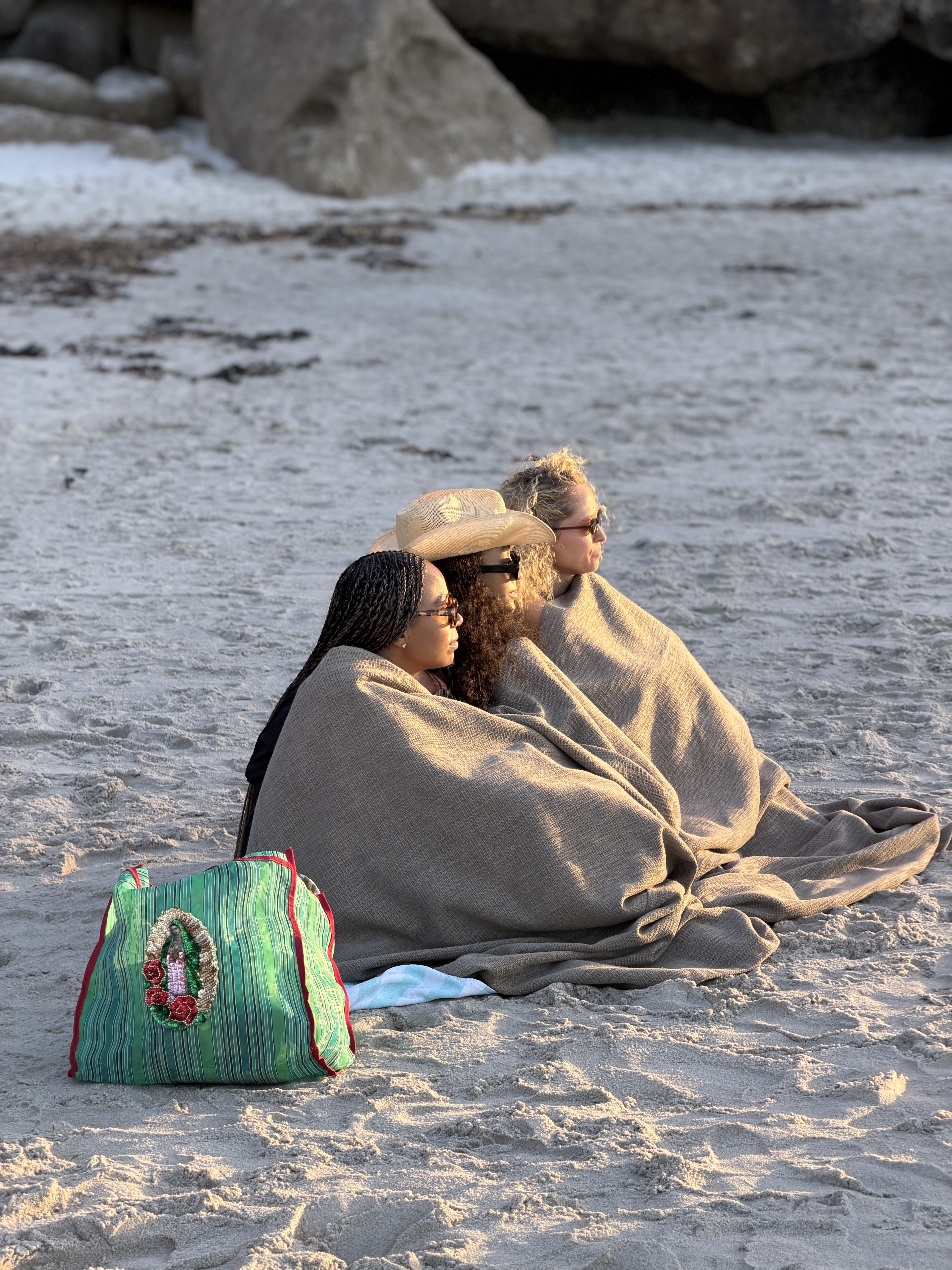 Friends wrapped in blankets together on the beach