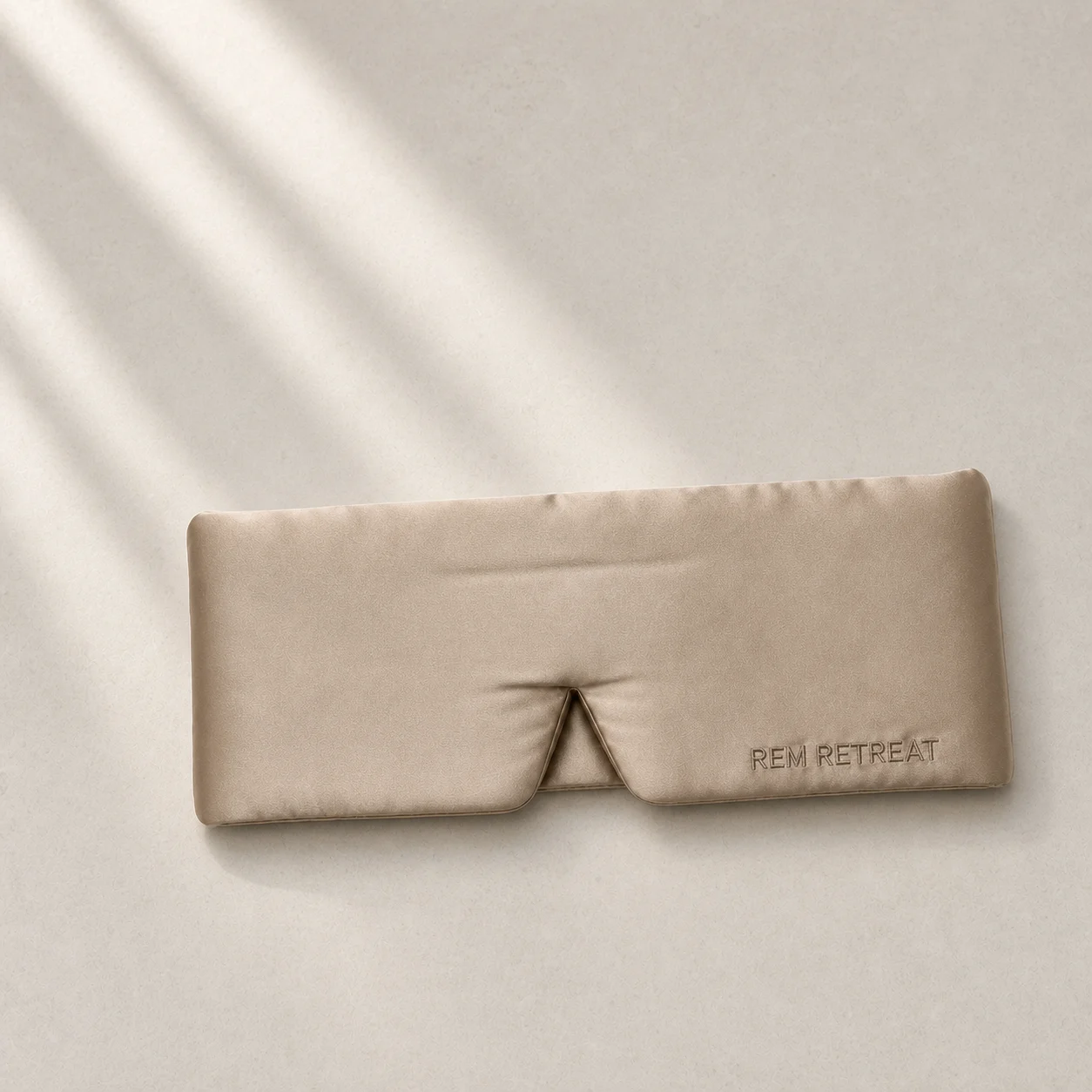 Champagne silk sleep mask on pale limestone in soft window light