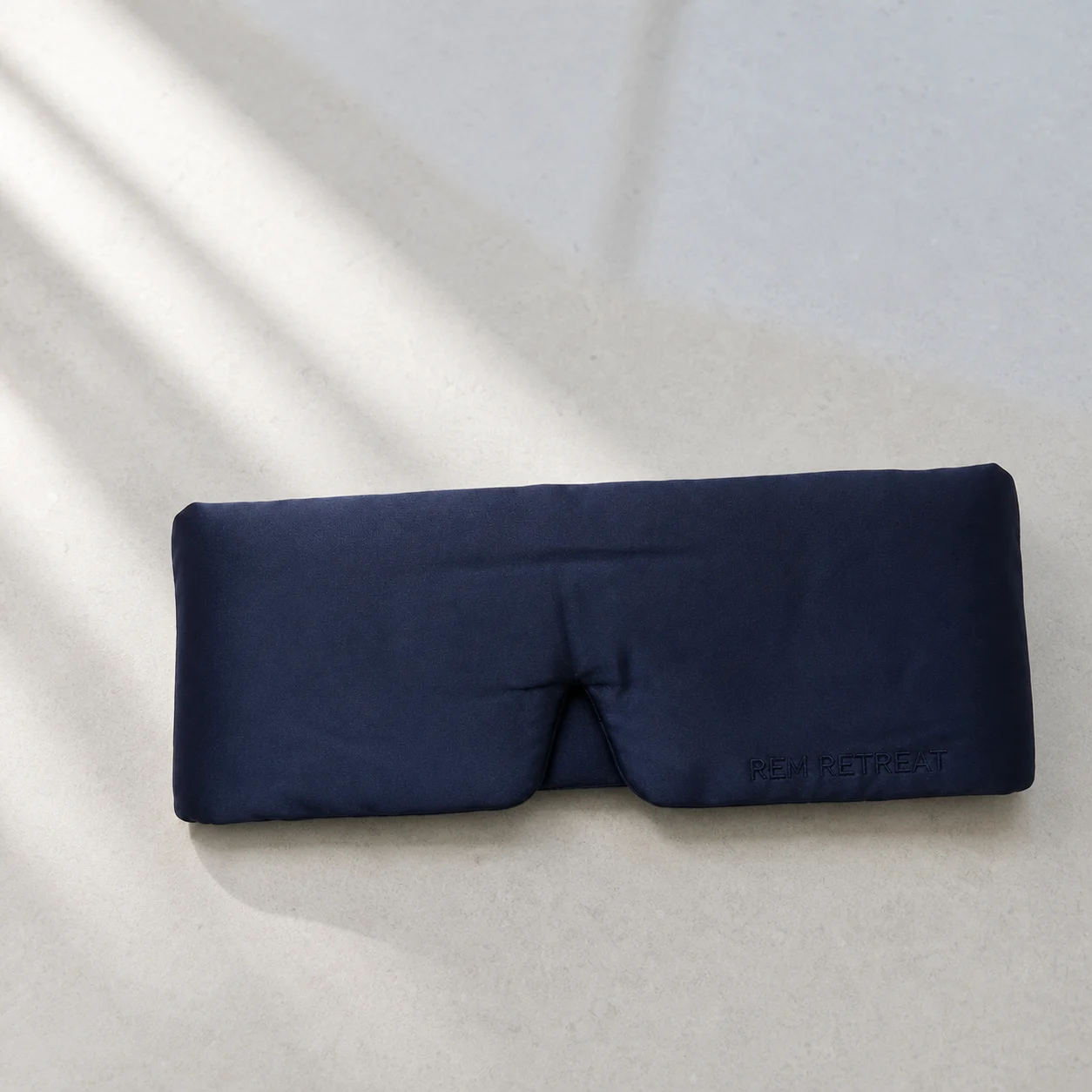Midnight Blue silk sleep mask on pale limestone in soft window light