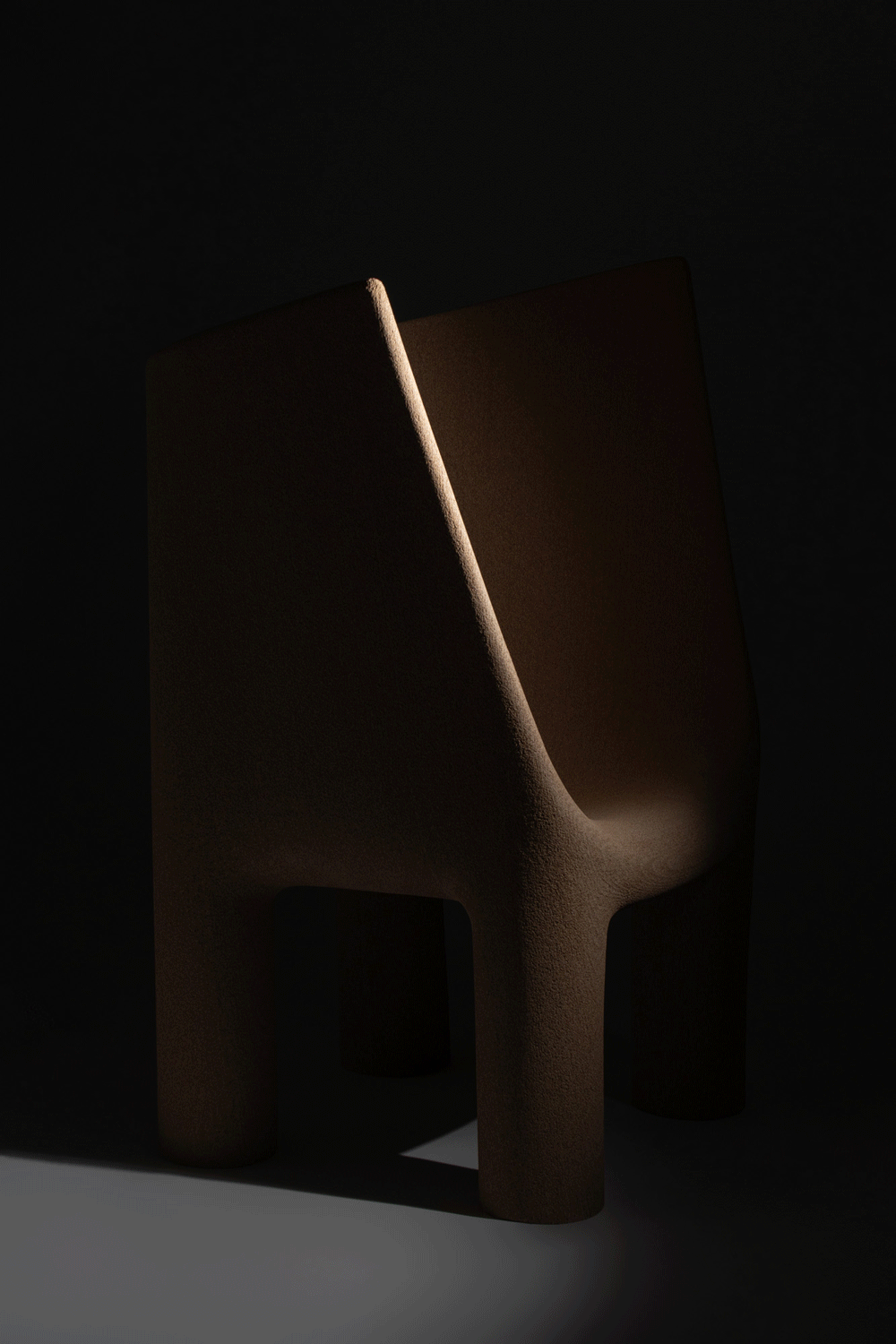 Three-quarter view of the Materia Futura chair — monolithic form crafted from Econit Wood, captured under soft light and shadow.