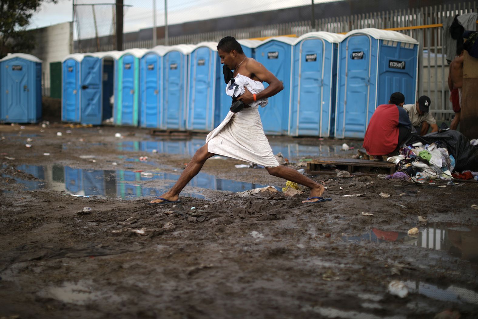 002_a man steps across mud after taking a shower at the shelter