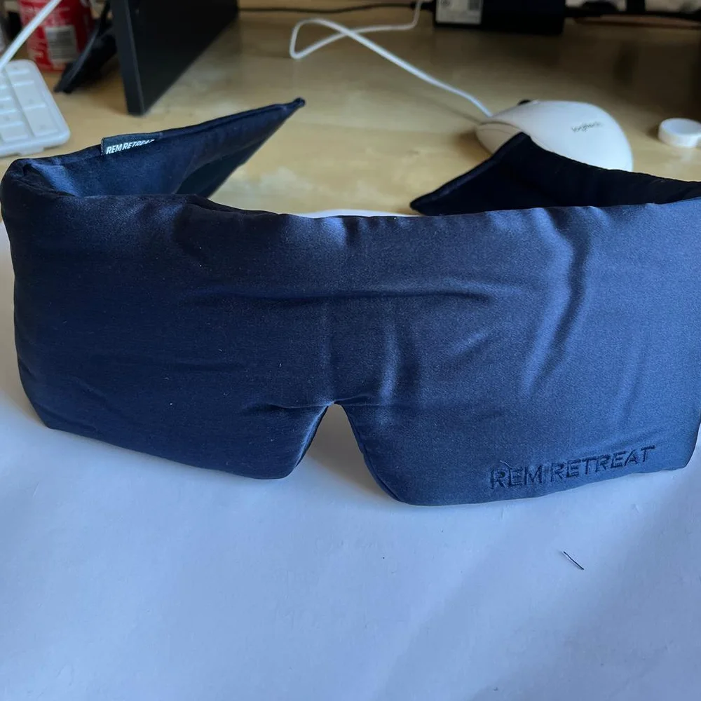 Client-supplied phone photograph of the Midnight Blue sleep mask, front view on white paper
