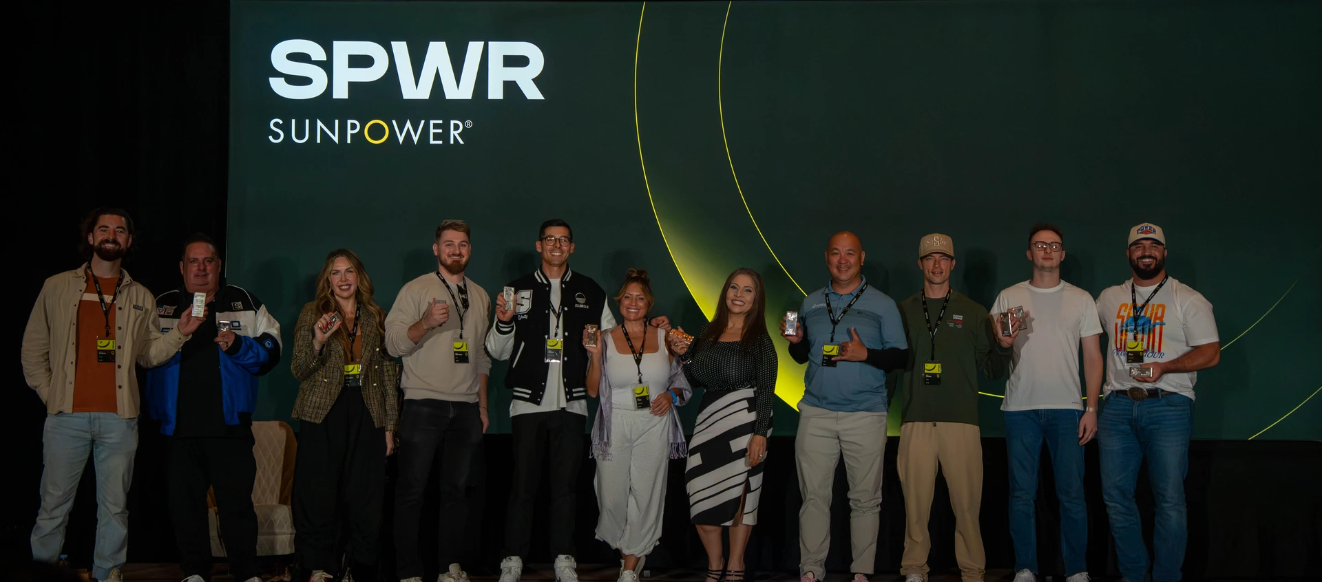Summit attendees on stage in front of the SPWR backdrop with yellow circular graphics.
