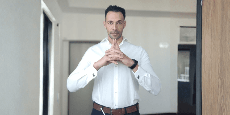Simone Giaquinto, in a white shirt, gestures while discussing his coaching book "CODE OF WAR" and its transformative insights.