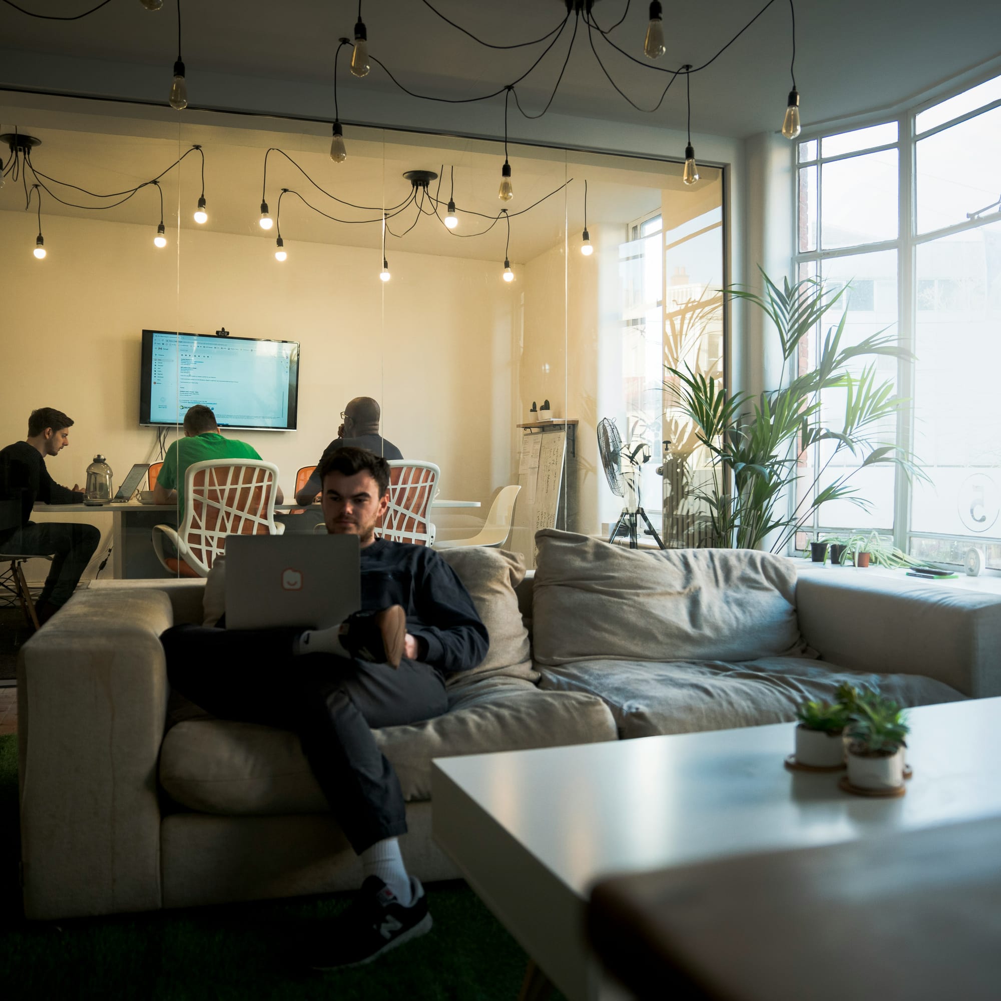 Medewerker werkt op een laptop in de kantoorlounge