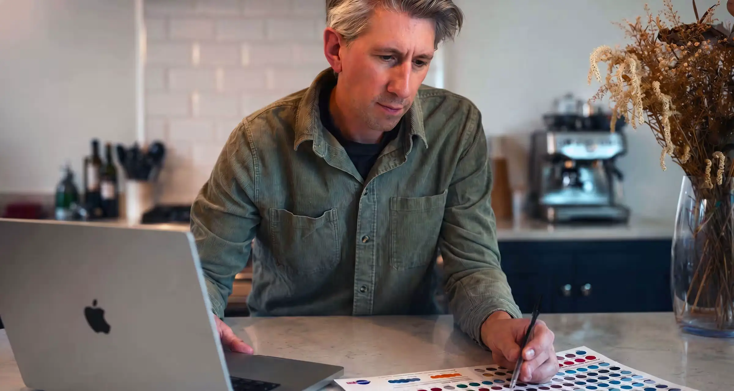 Thomas Harvey, Senior UK Freelance Graphic Designer and Artwork Specialist working at laptop with print color proof sheet