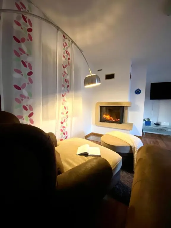 A smiling young man with crossed arms, wearing a plaid shirt and white t-shirt, poses against a dark background.