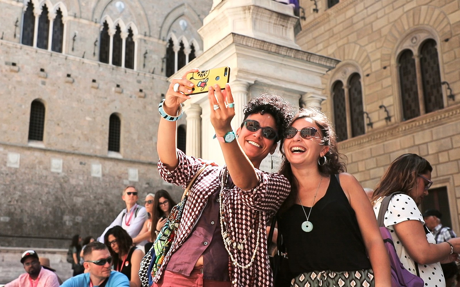 Tourists taking a selfie in front of historic architecture in San Gimignano, Italy.