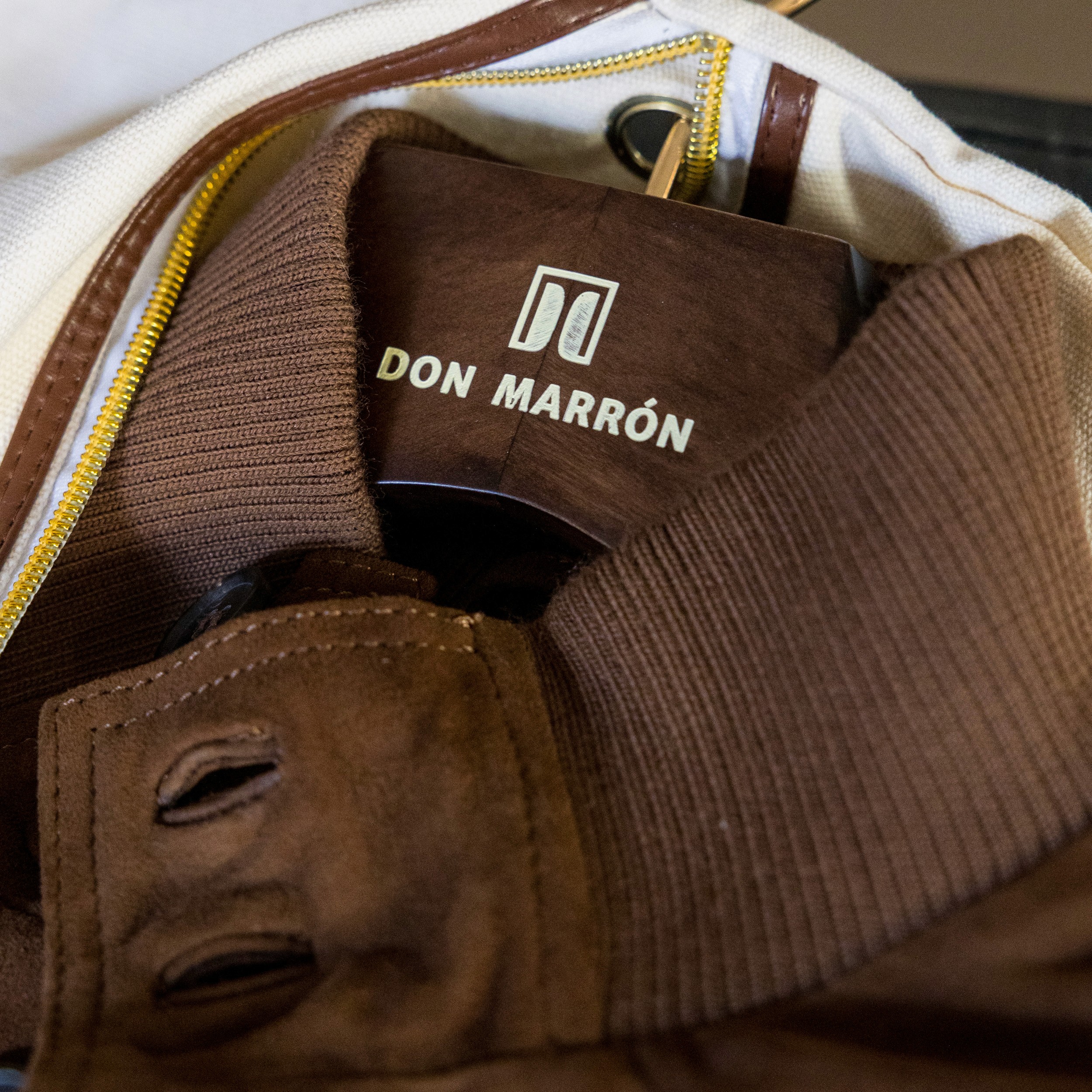 Man in a tailored jacket touching his reflection in a window, symbolizing introspection and refined modern menswear.