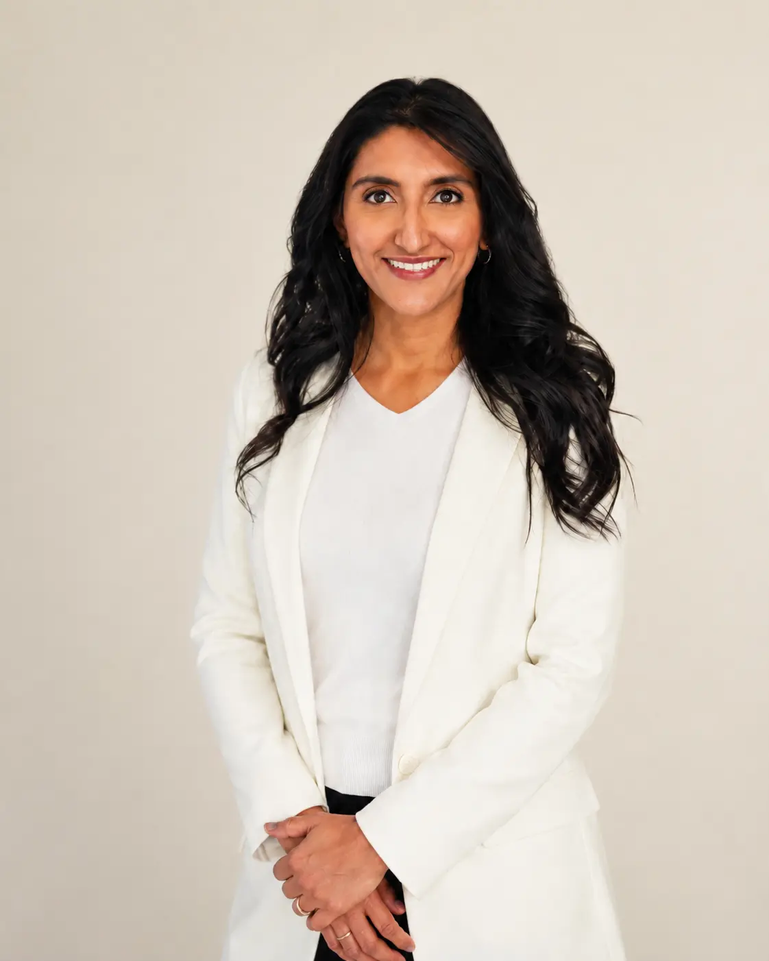 Portrait of a smiling woman with long dark hair in a white blazer