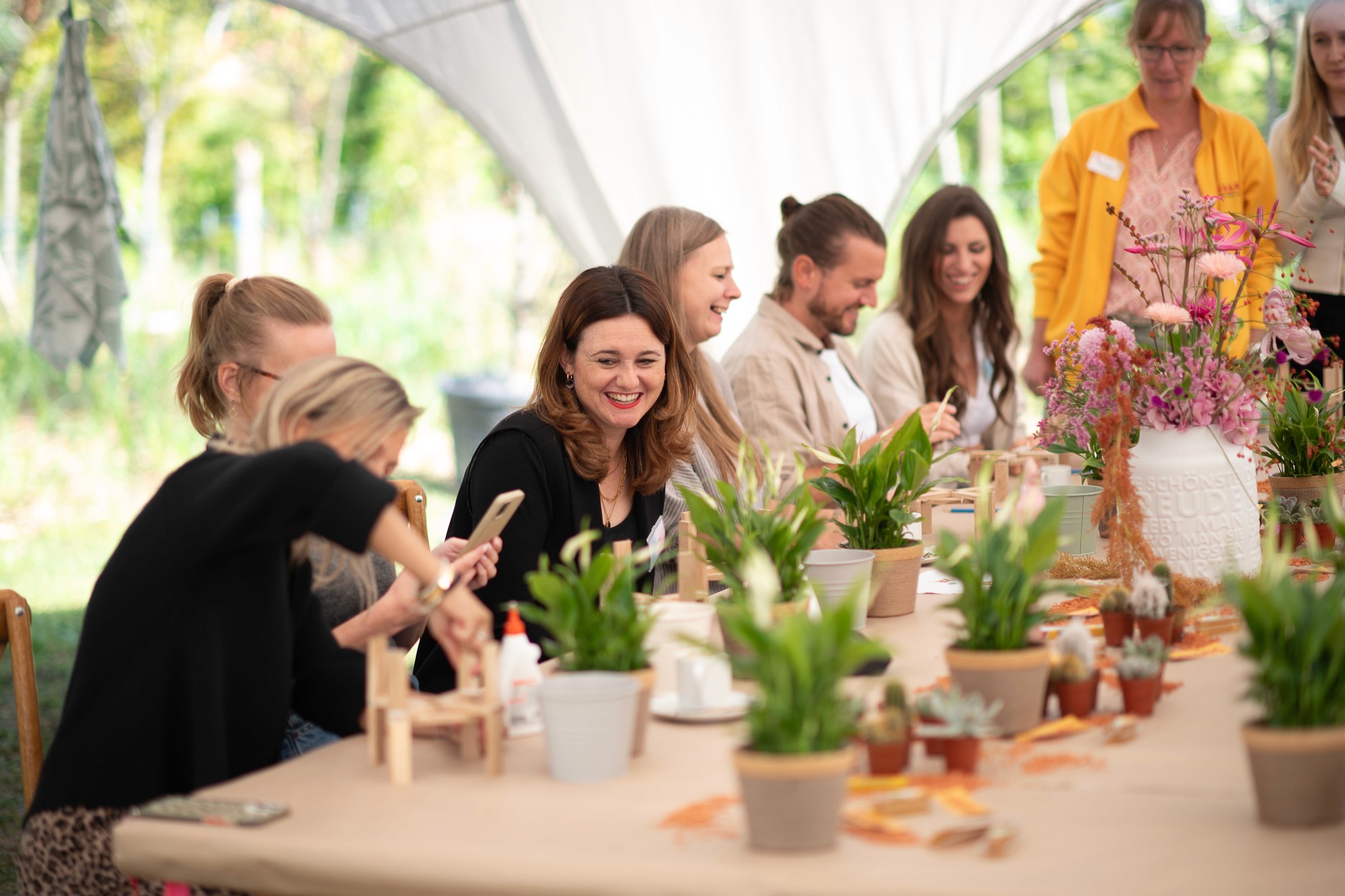 Teilnehmerinnen arbeiten gemeinsam an einem Kreativ-Workshop mit Pflanzen und Bastelmaterialien