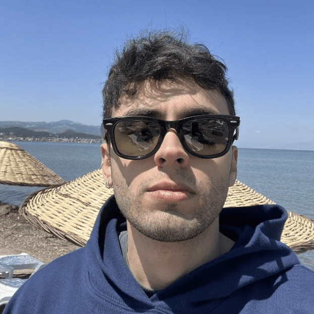 Man wearing sunglasses and a hoodie near the seaside.