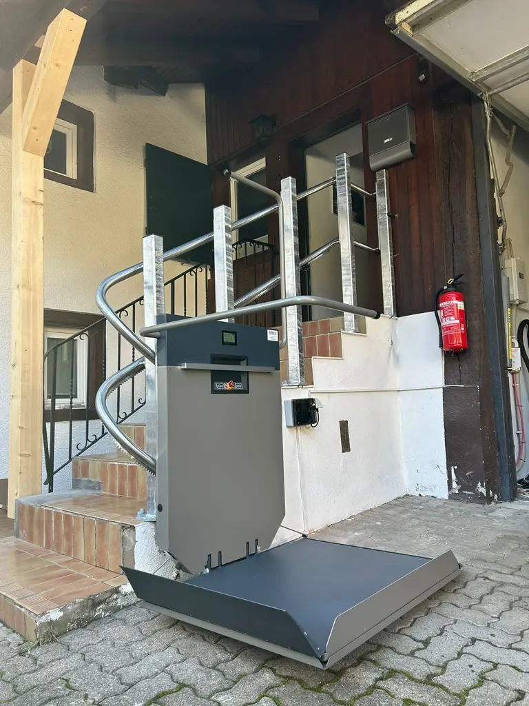Plattformlift mit abgesenkter Plattform an einer gefliesten Eingangstreppe