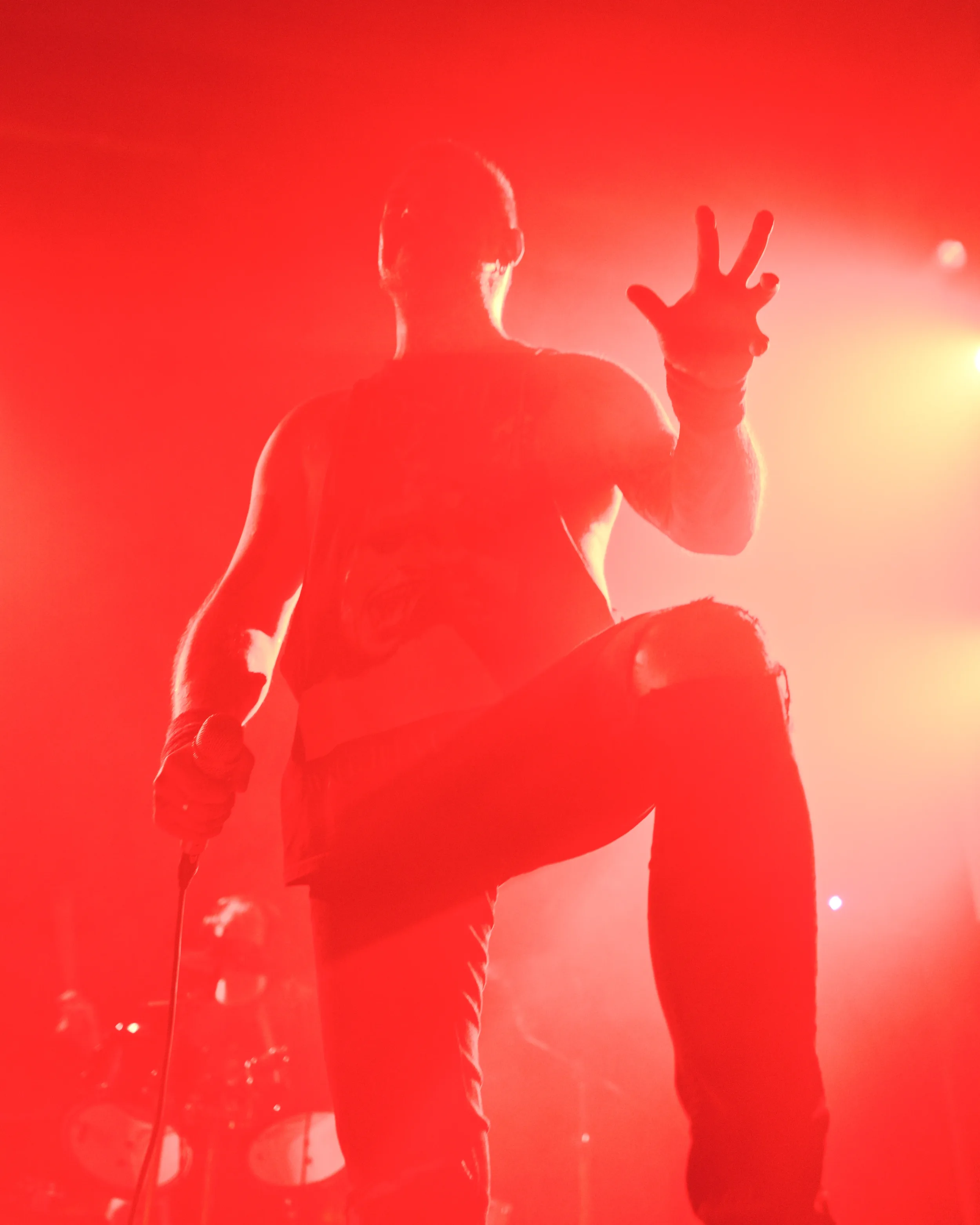 Photographie impactante d'un chanteur de métal se découpant dans un faisceau de lumière rouge saturée