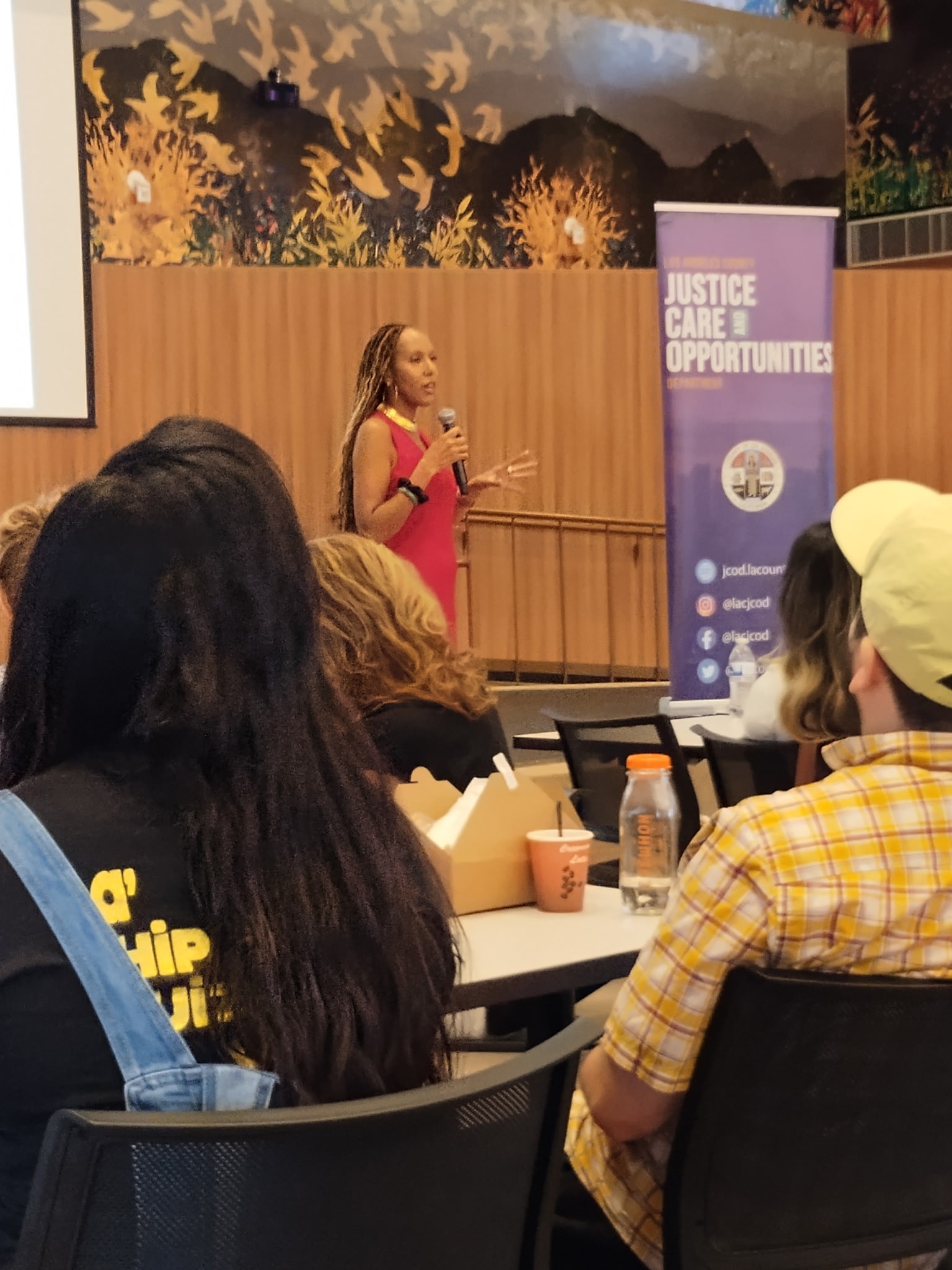 A woman in motion during a yoga session in a light-filled modern room with large windows, wood floors