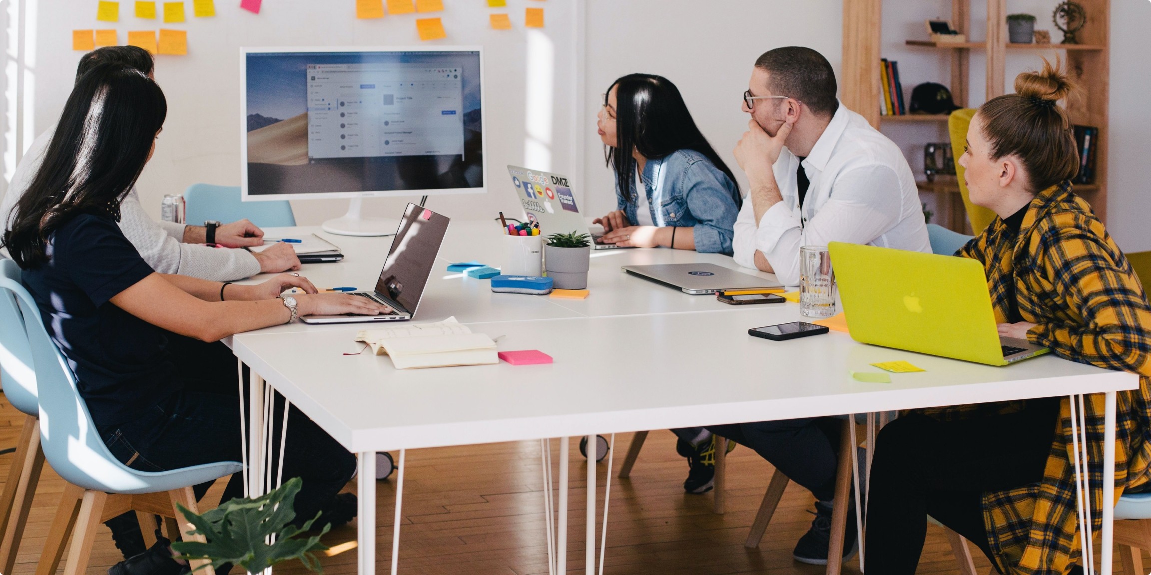 Decorative image of a work group sitting at a table and looking at a computer screen.