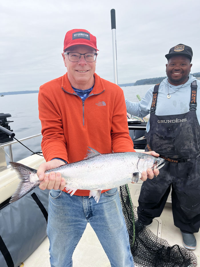Angler with chrome salmon on guided Puget Sound king charter.