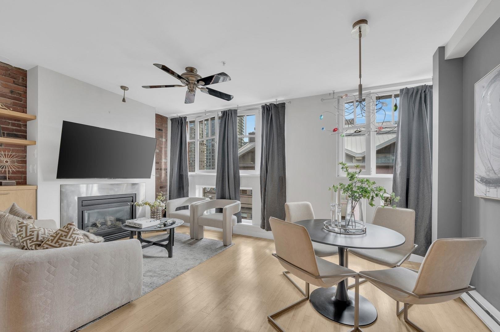 A modern living room with a dining area, featuring light wood flooring, large windows, and contemporary furniture.
