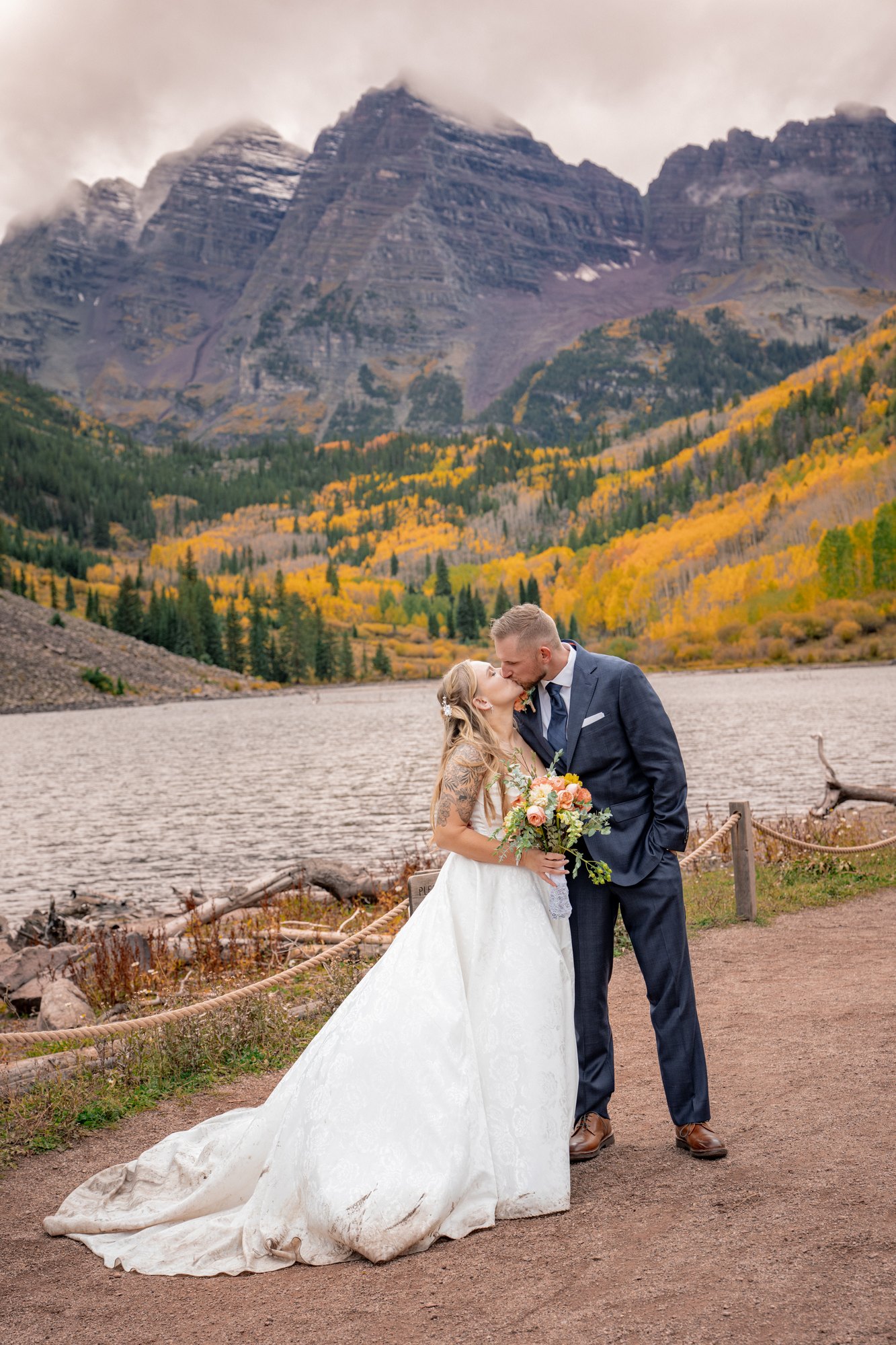 Wedding couple sharing a kiss beside Maroon Lake with the mountain peaks behind them