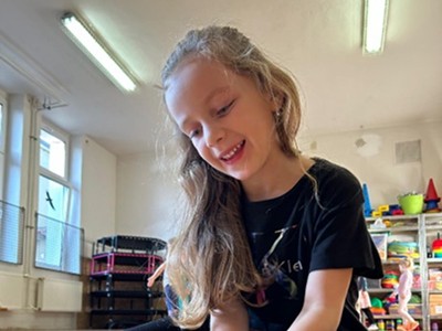 Portrét usměvavé holčičky s dlouhými vlasy ve třídě