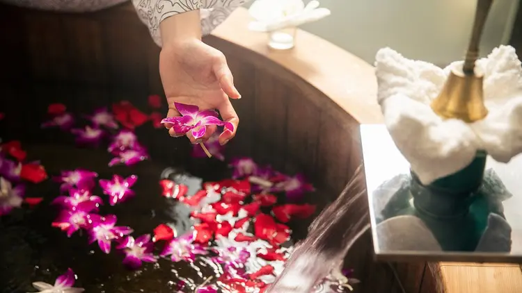 Guest enjoying, bath tub in the spa with fresh flowers floating on the water