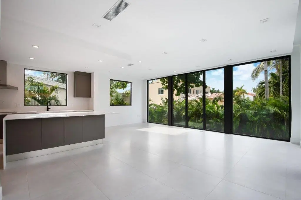 Open plan kitchen and living area with floor-to-ceiling glass in modern Miami Beach residence by Atelier International LLC