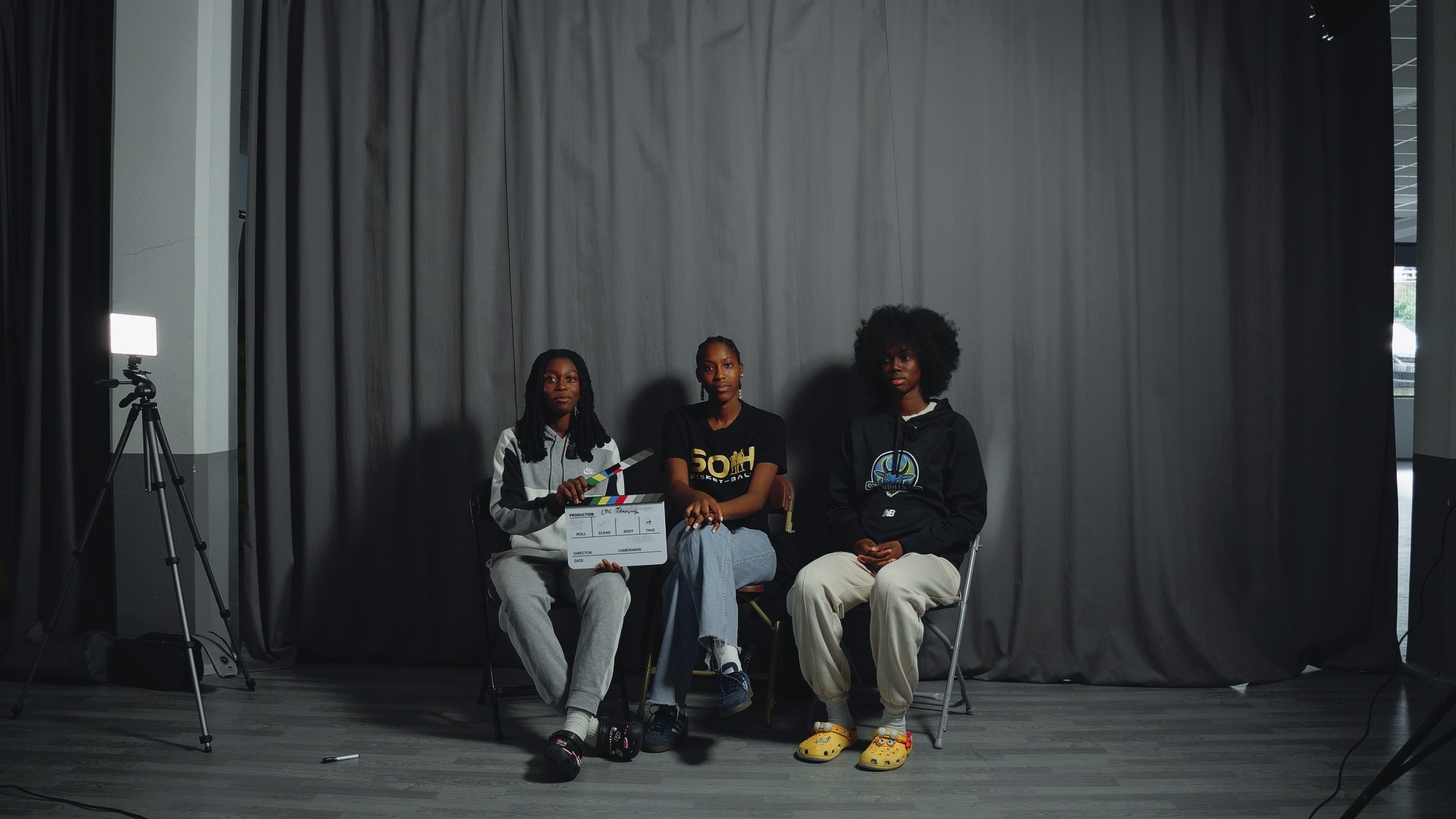 Session de témoignage en studio avec trois athlètes, un clap de tournage visible à gauche.