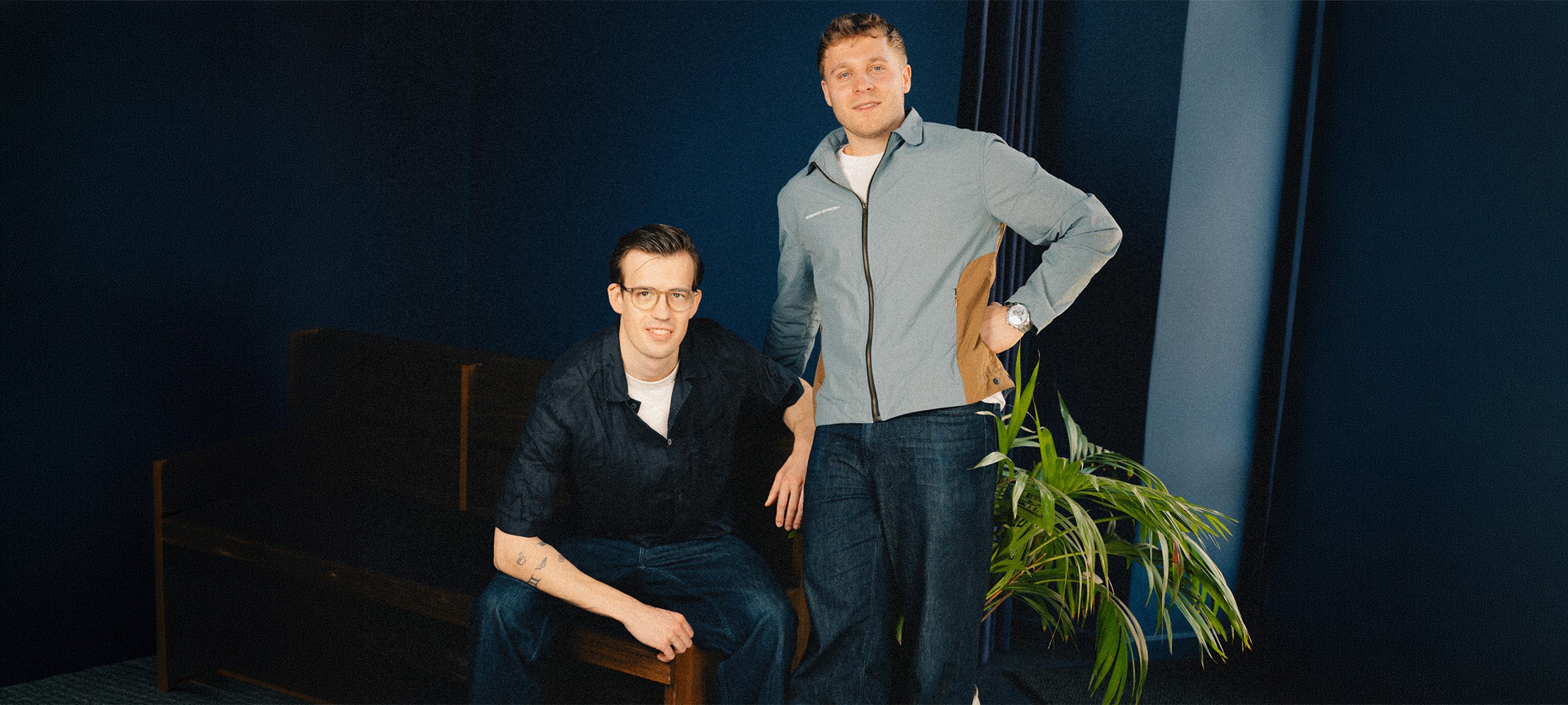Group of peole running on top of a long hill covered in grass and flowers.