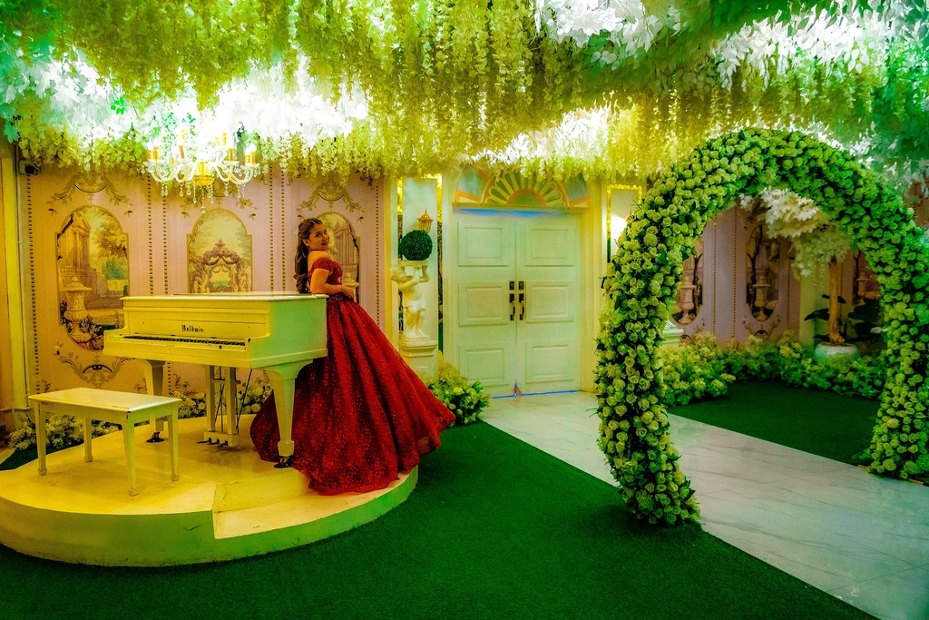 Debutante in red beside the piano and garden arch at Celestia Hall