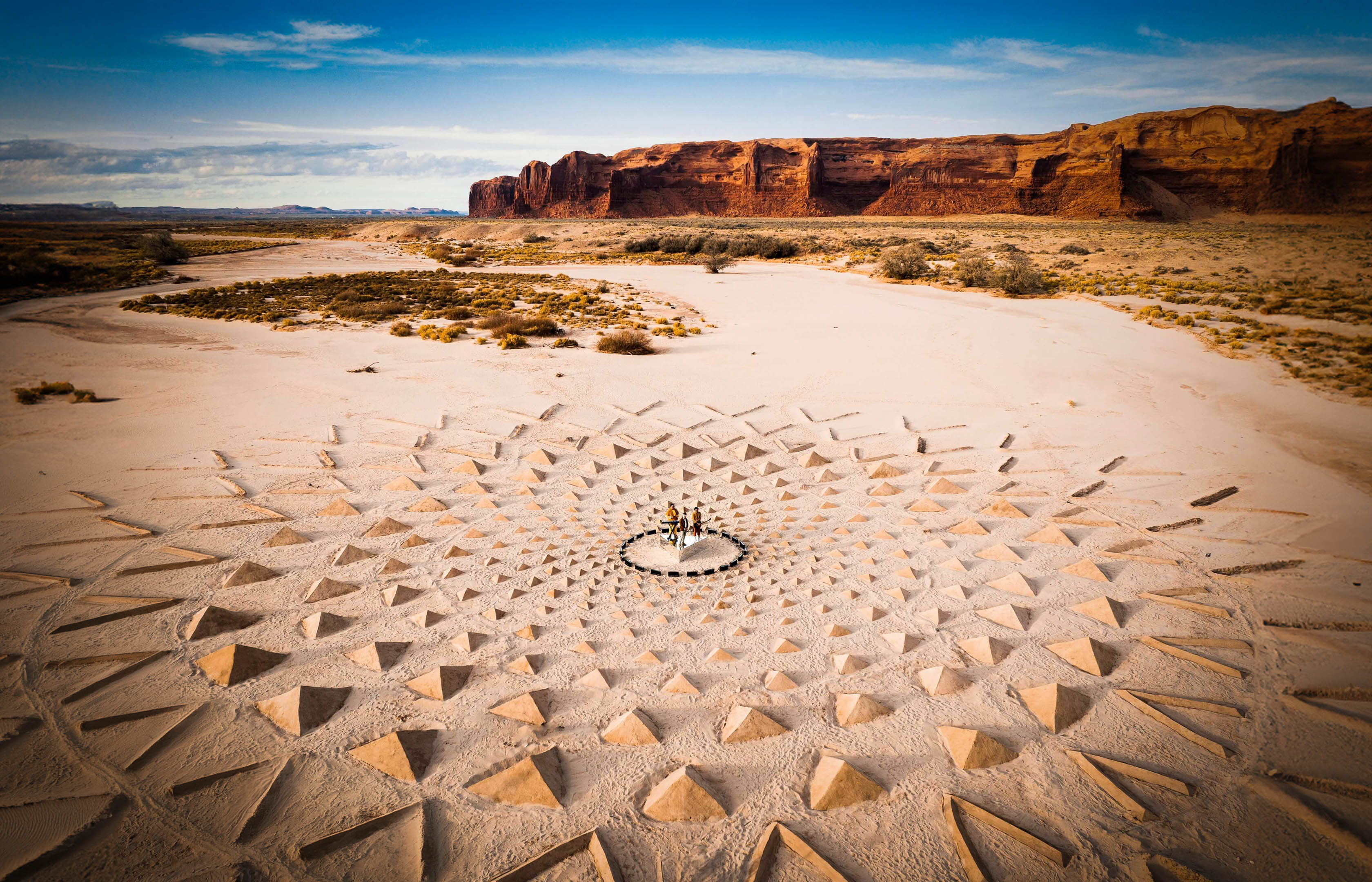 A drone photo of land art made out triangles in front of red rock formations in Arizona