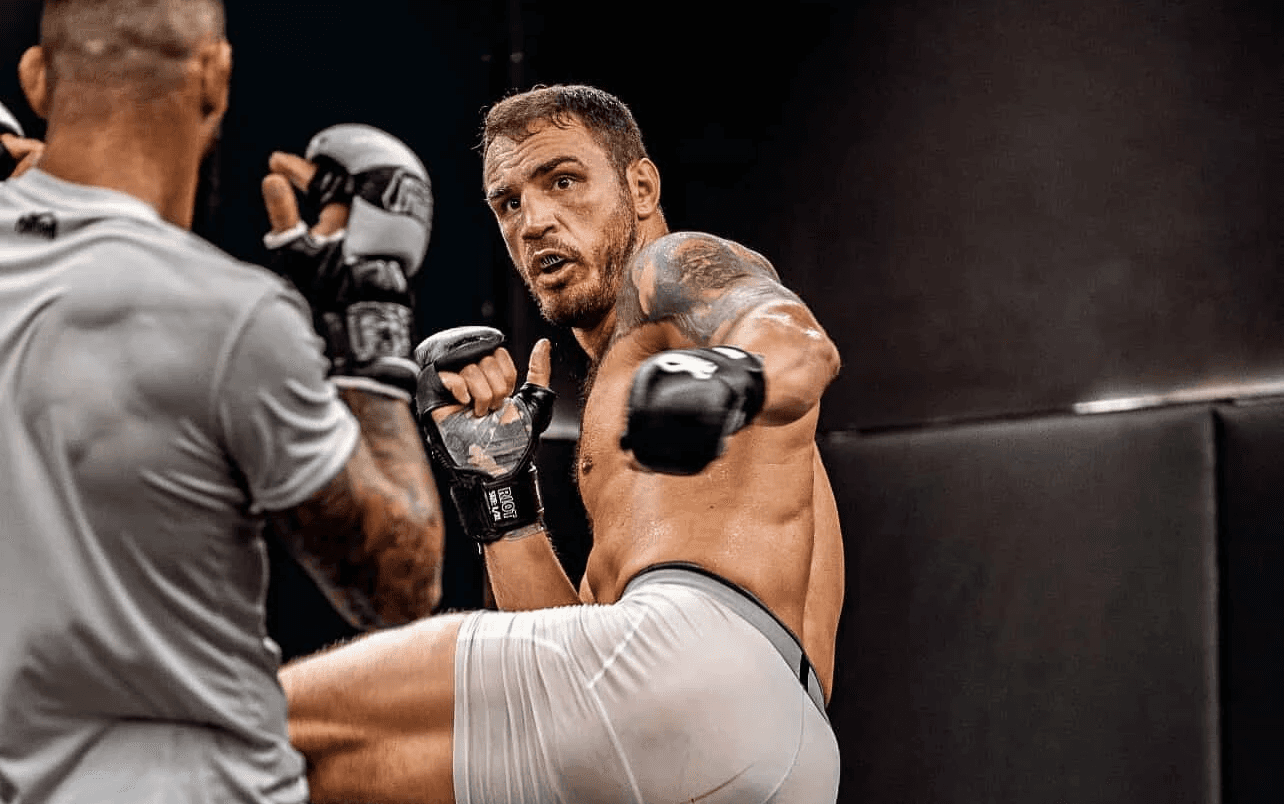 Agron Smakici and client smiling in boxing gear at a training facility after pad work and conditioning.