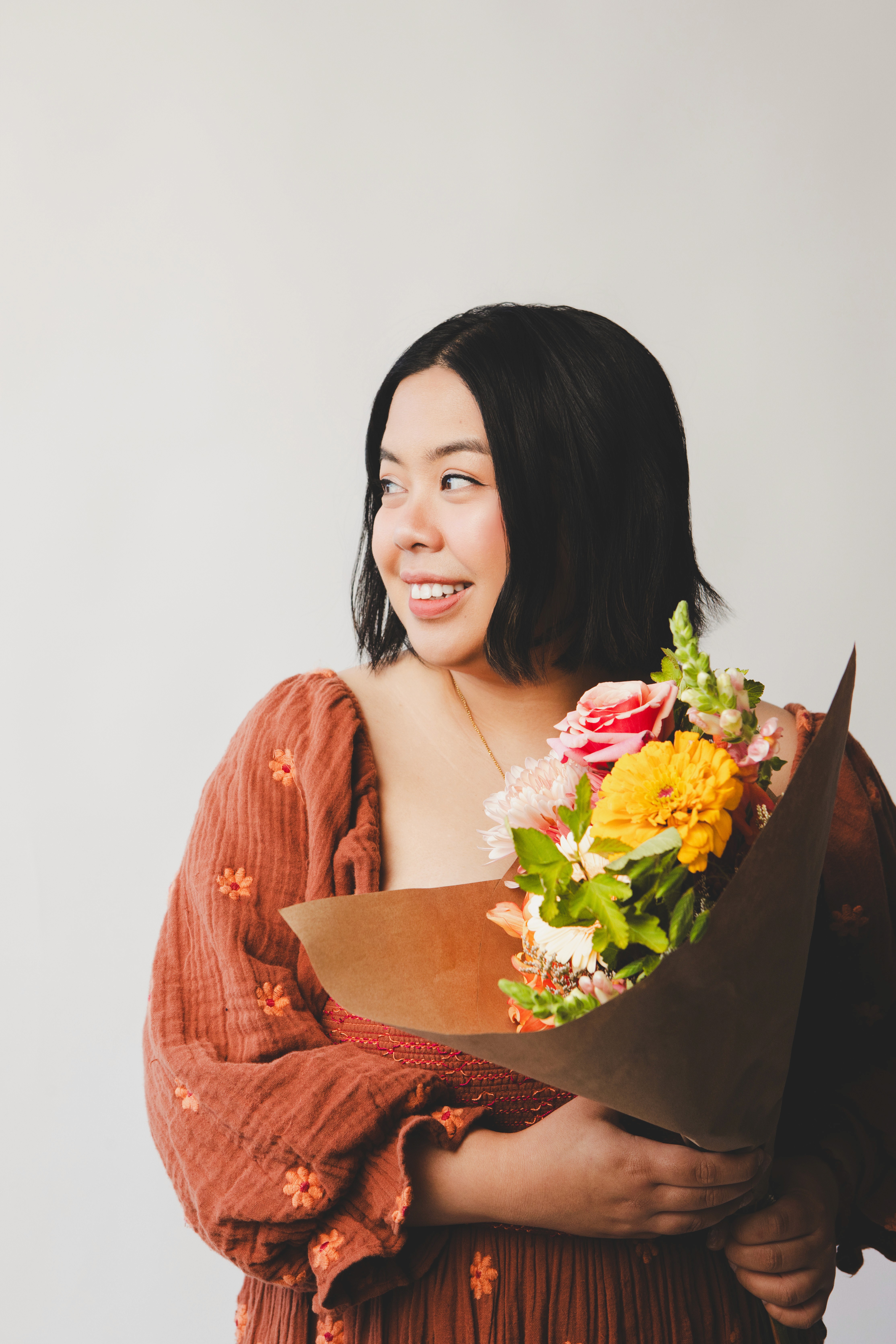 Designer in orange dress holding bouquet of flowers