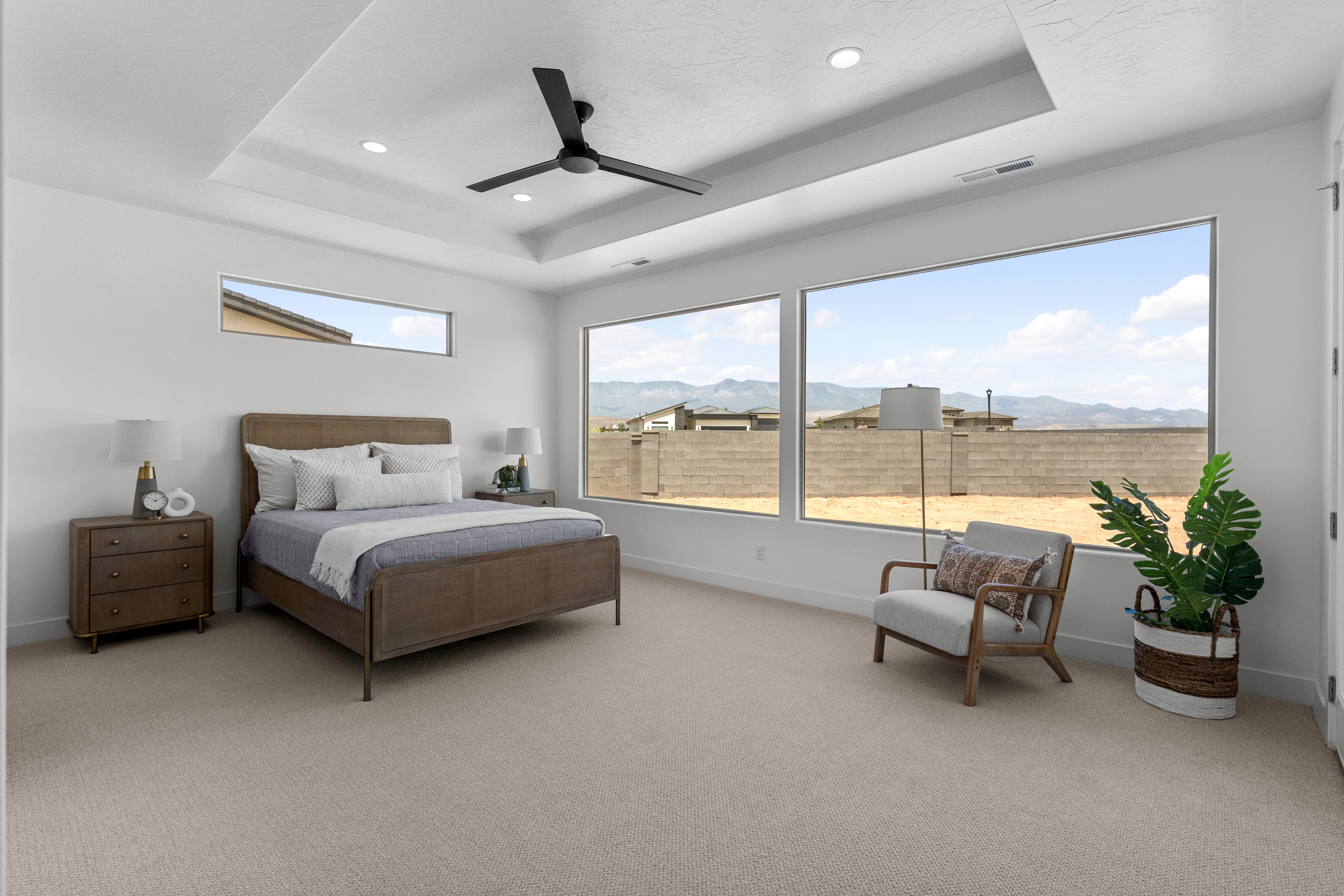 Master bedroom in The Nest at Falcon Ridge with large windows, ceiling fan, and carpeted flooring.