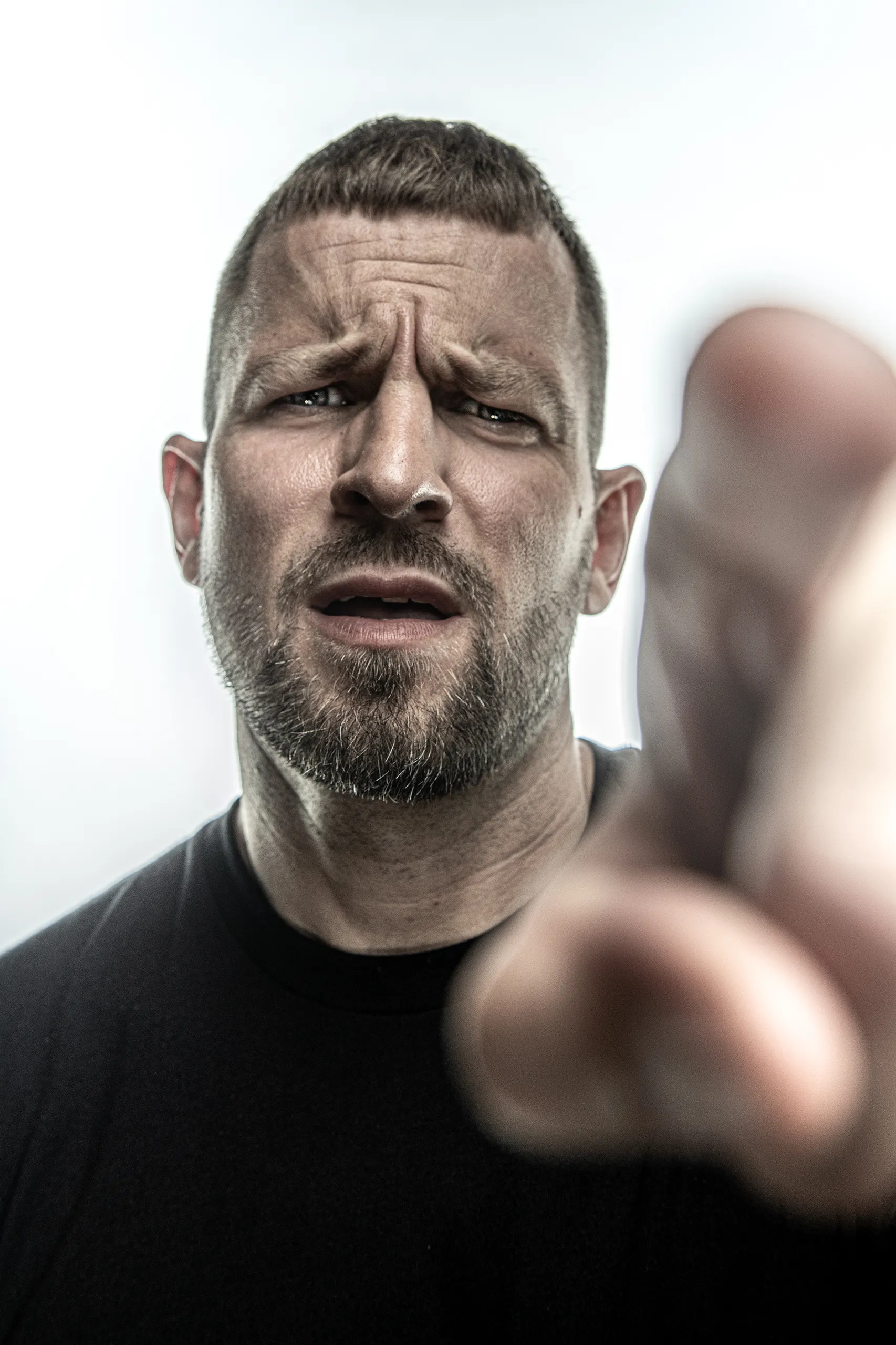 Aggressive and powerful portrait of rapper Stress pointing toward the lens.