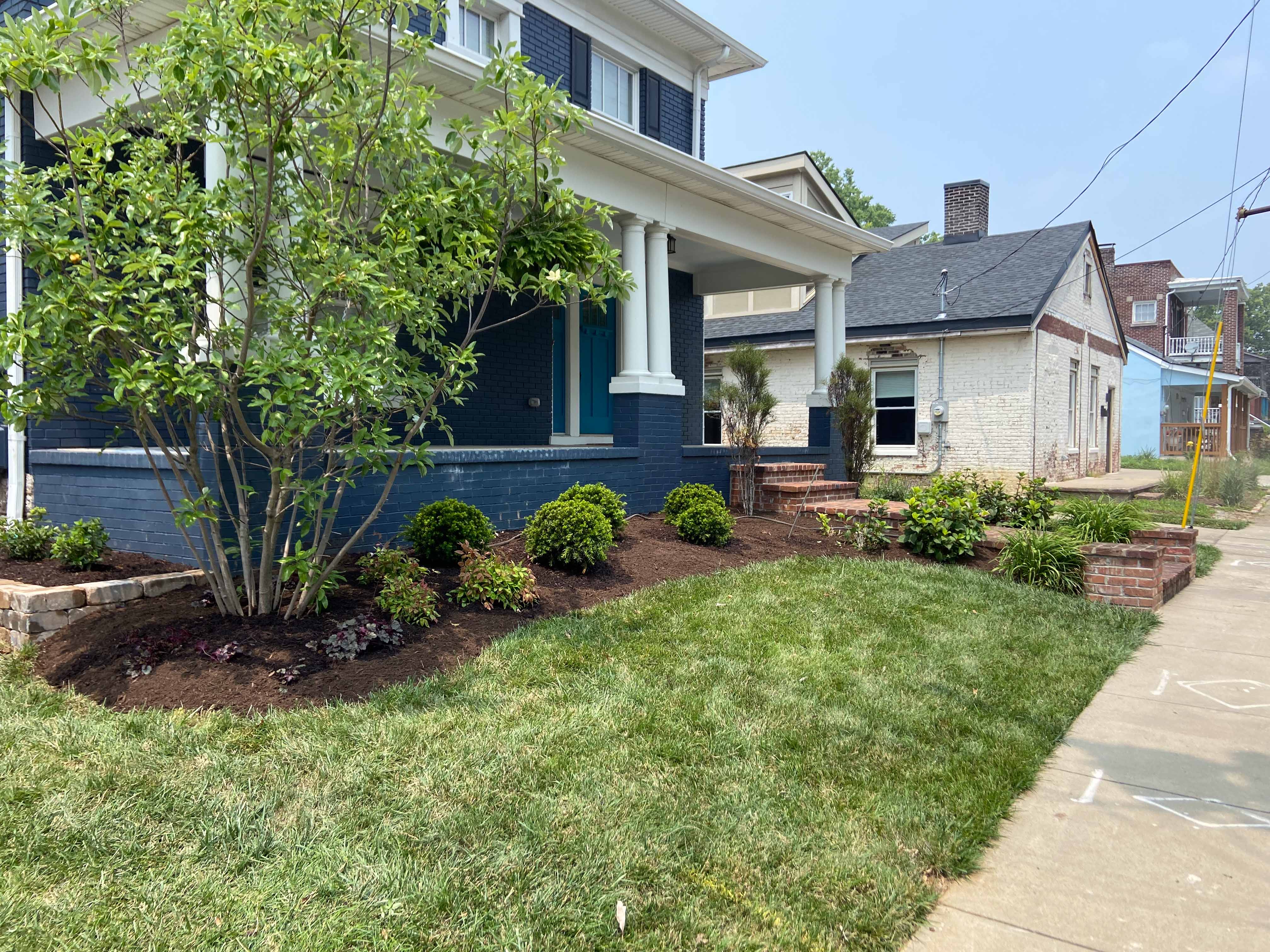 Blue house front with manicured lawn and fresh landscaping.