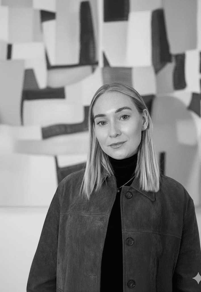A thoughtful young person with dark hair gazes to the side, captured in soft black and white lighting.