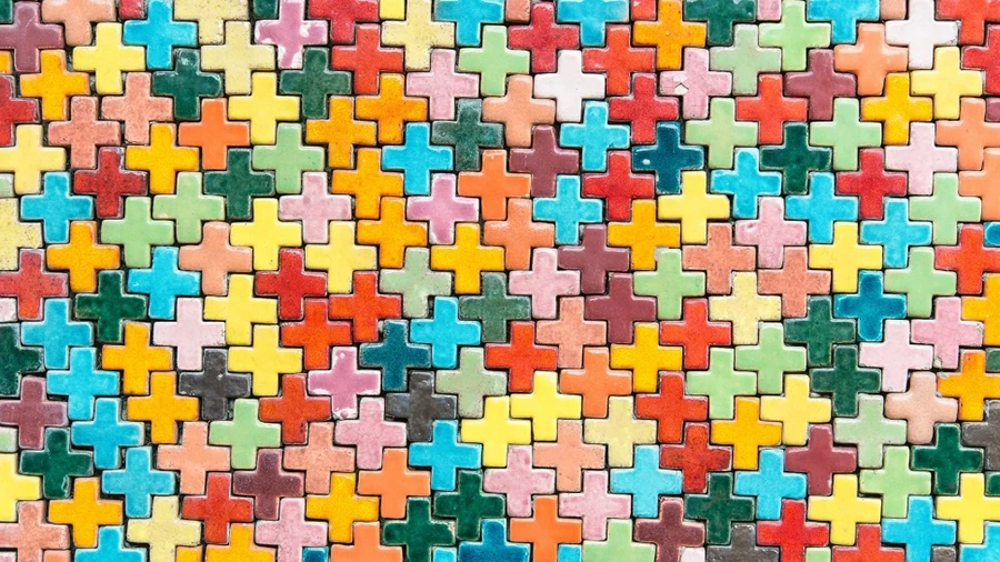 Colorful interlocking plus-shaped tiles arranged in a seamless pattern.
