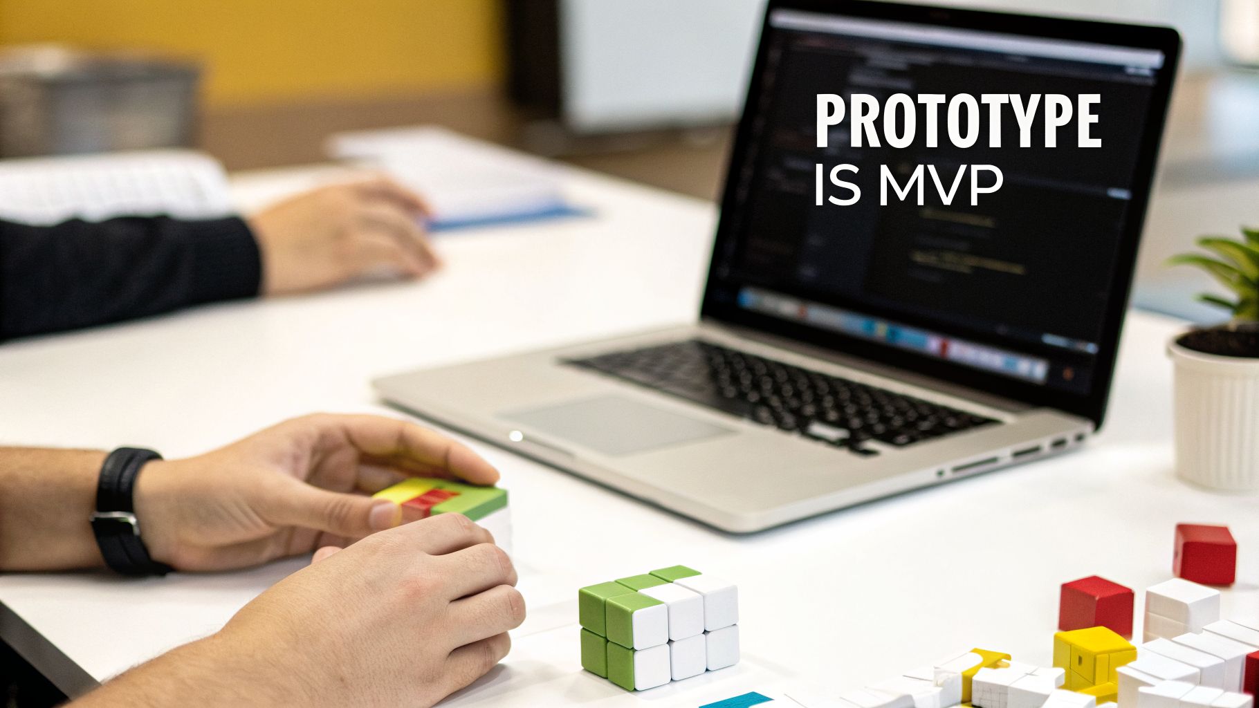 Two people collaborating, one holding colorful building blocks, with a laptop displaying 'PROTOTYPE IS MVP' on a table.