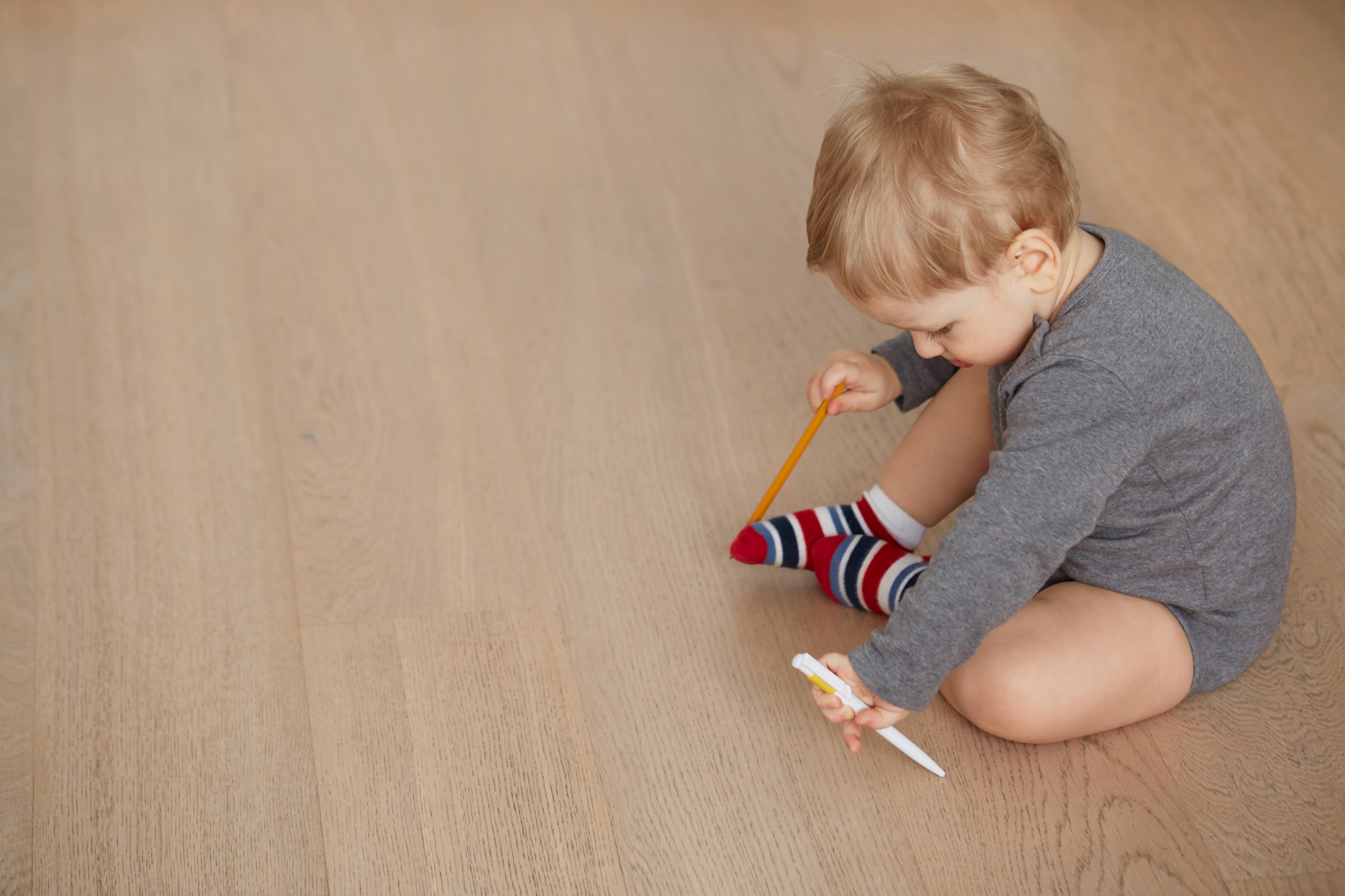 Baby sitting and playing on smooth, low-VOC flooring, supporting safe, comfortable living for growing families.