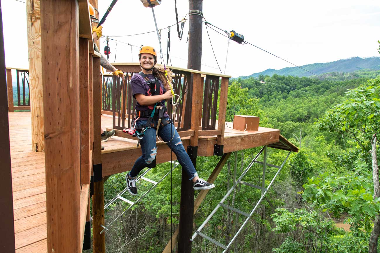 A smiling girl taking off from the 3 story rappel drop