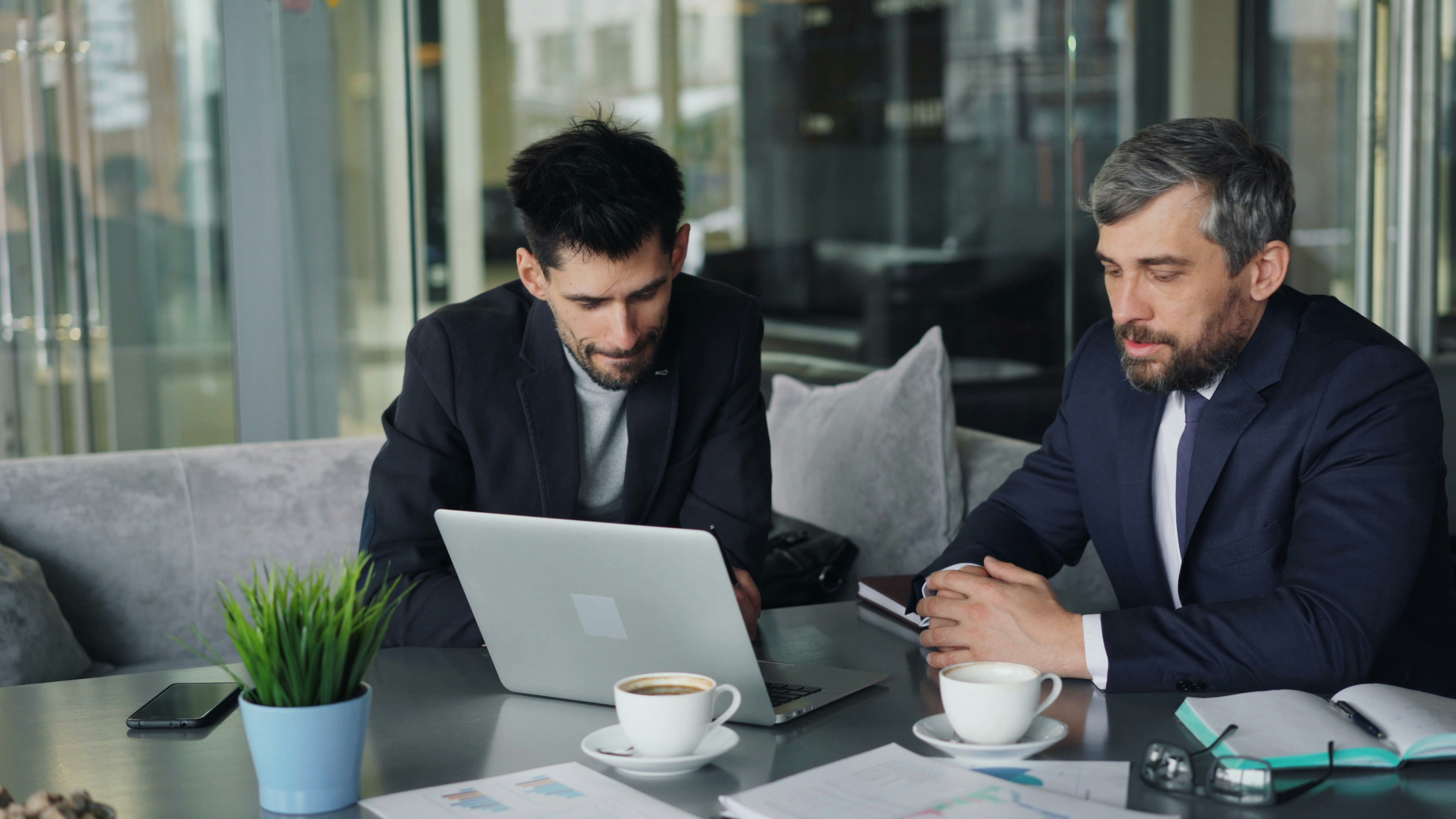 Two professional businessmen discussing data on a laptop in office.