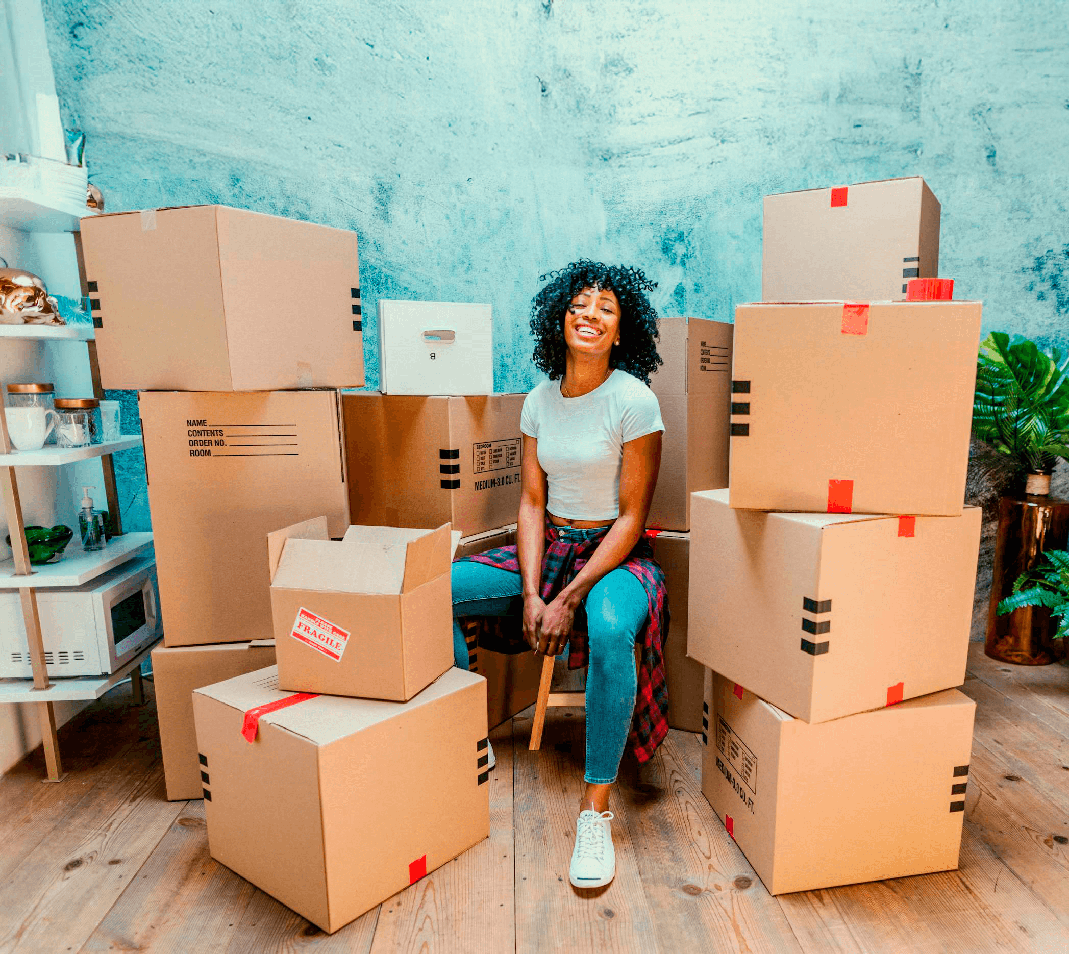 Women with moving boxes around her, inside the house, smilling.
