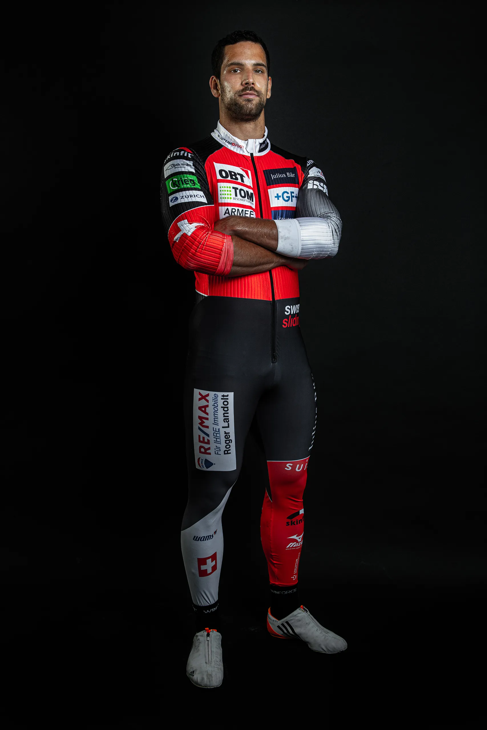 Bobteam Vogt athlete with arms crossed in a clean studio portrait in race suit