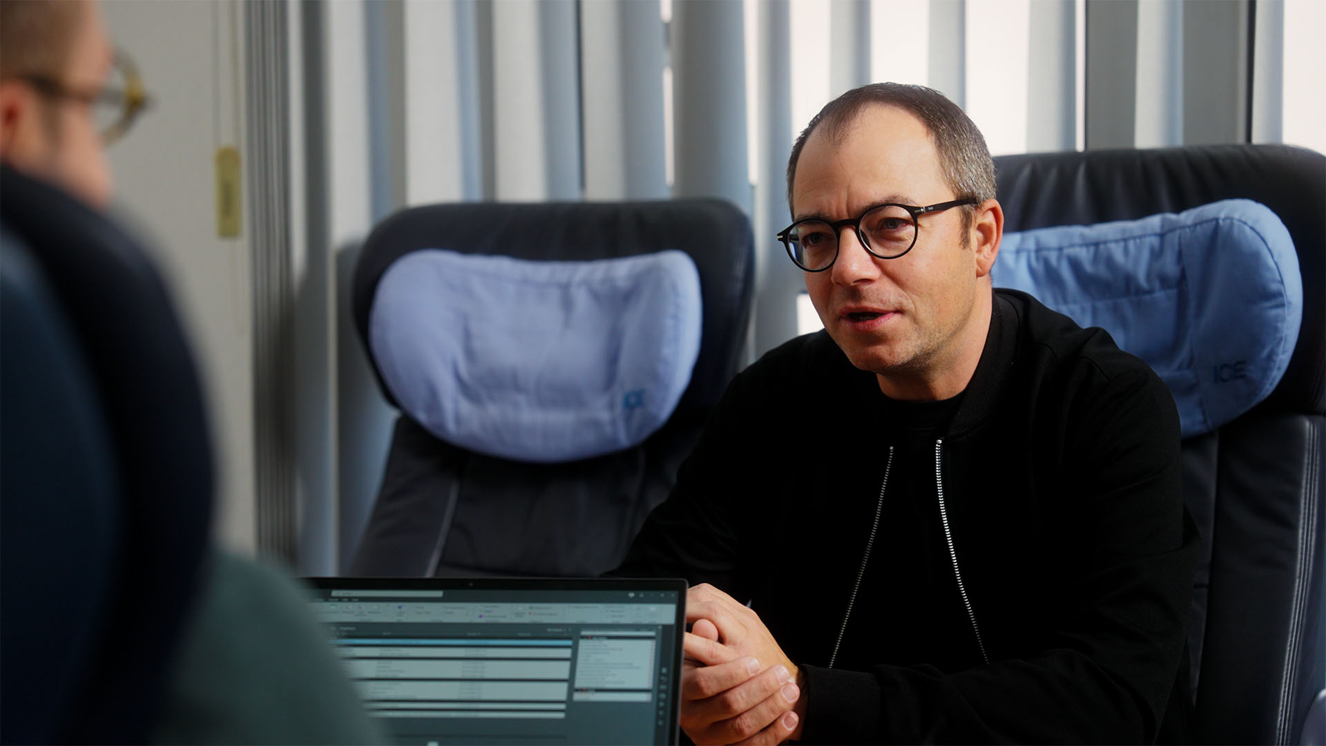 Man in conversation on train discussing strategic filmproduction and advertising campaigns for social media.