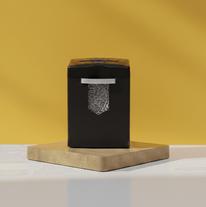 Sleek black professional-grade paper shredder on a wooden pedestal, demonstrating secure document destruction.