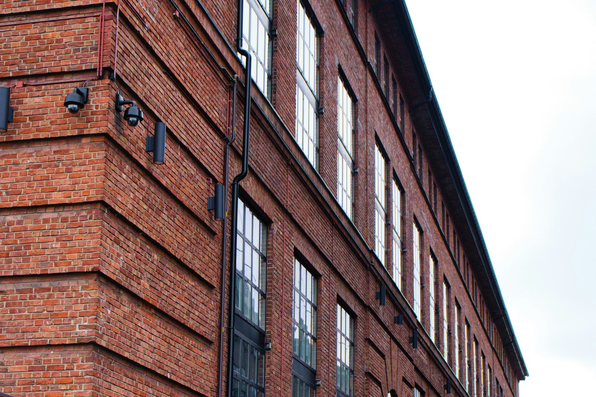 The brick side of an old mill building with rows of tall windows